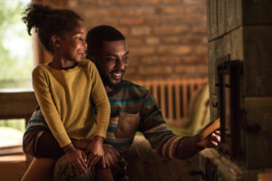 man smiling holding child next to furnace