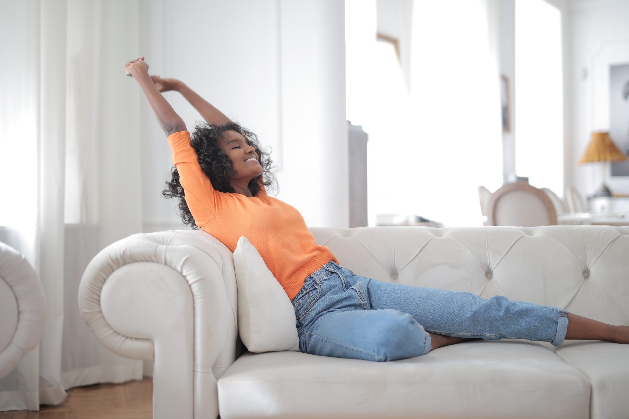 woman relaxing on couch and stretching her arms out