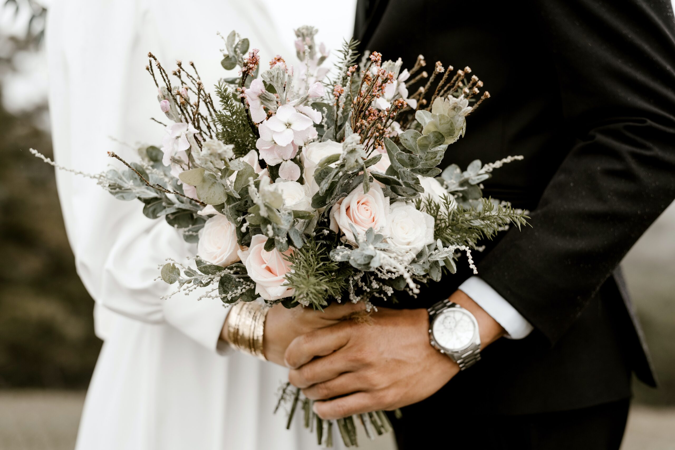 A closeup of a married couple holding a wedding bouquet