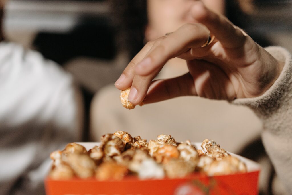 A closeup of a woman eating popcorn while watching a movie