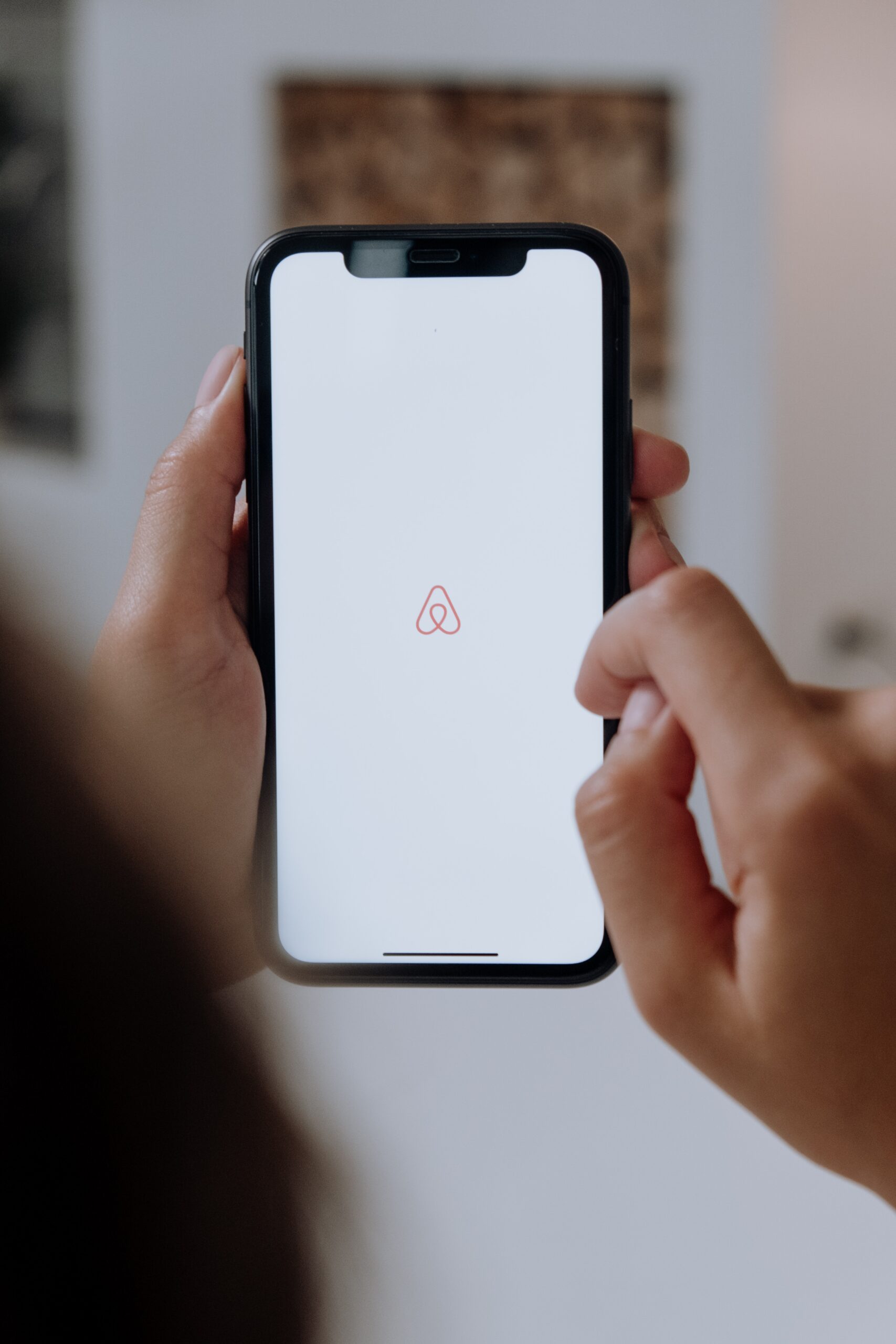 A closeup of a person opening the Airbnb app on their mobile phone