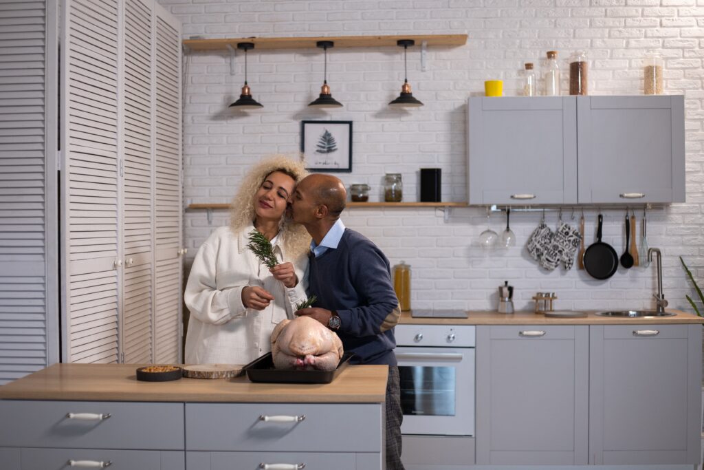 A man kissing his wife in the kitchen