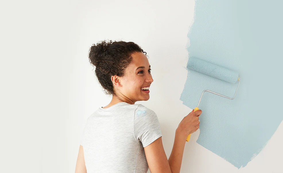 A woman painting a white wall