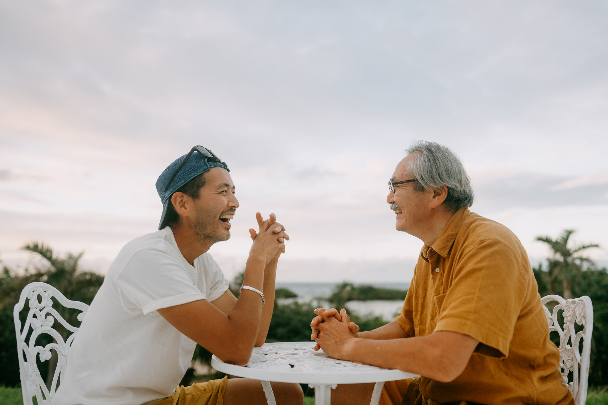 Cheerful senior father and adult son chatting on patio, Japan