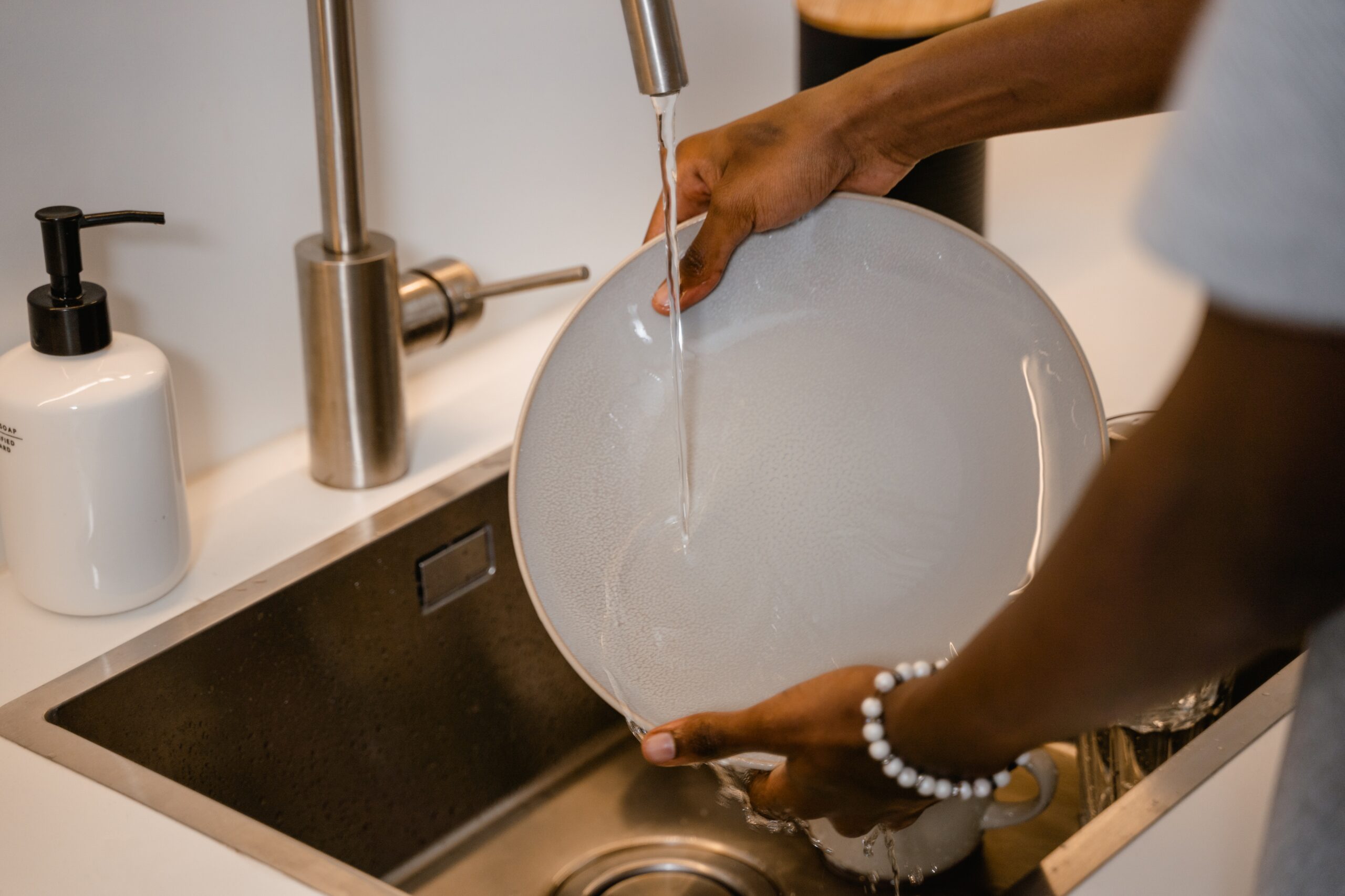Person handwashing dishes in sink