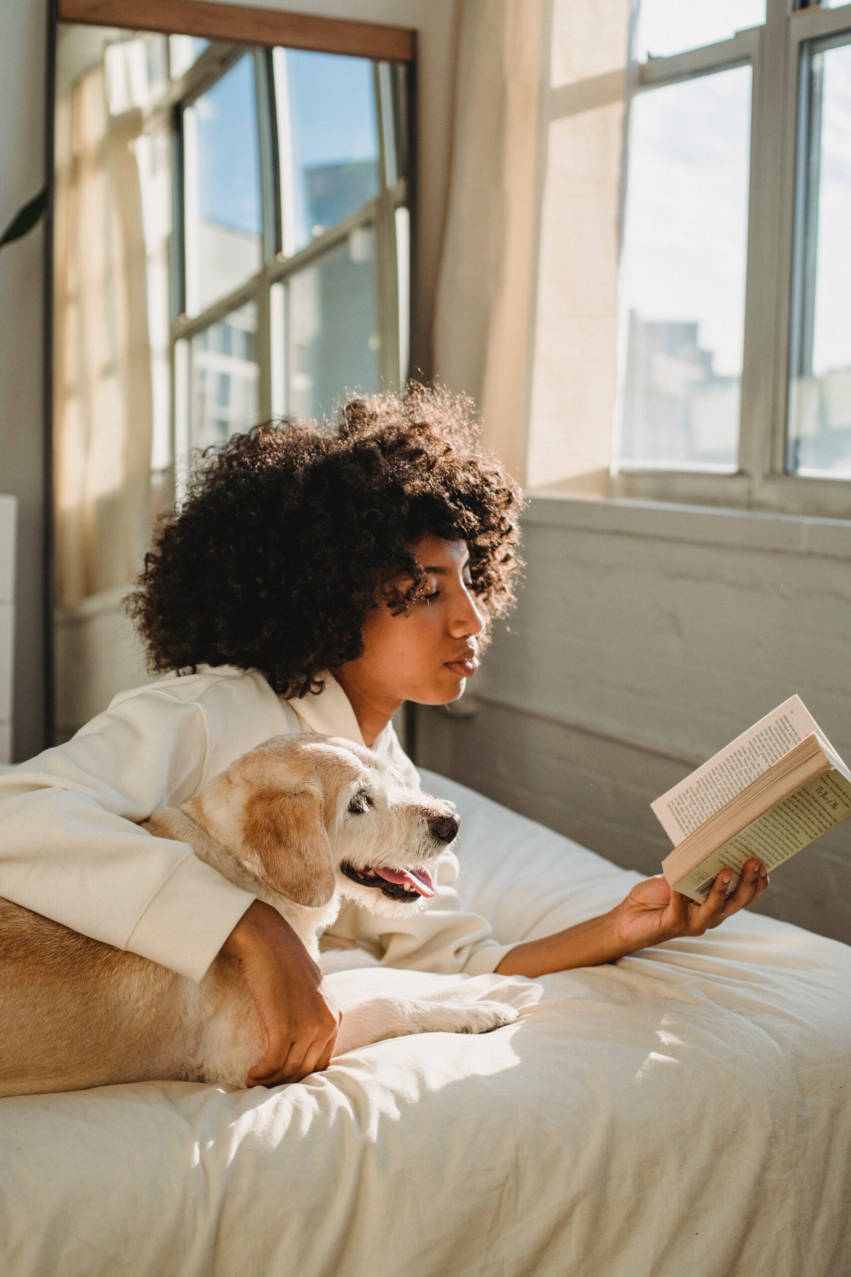  Woman reading book with dog on bed