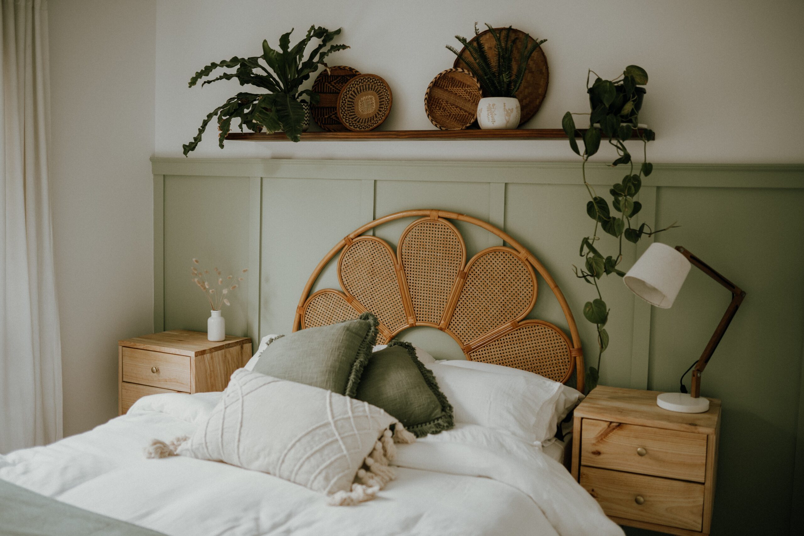 A sage green room with dark green pillows and leaf decor. Pictured: A bedroom.