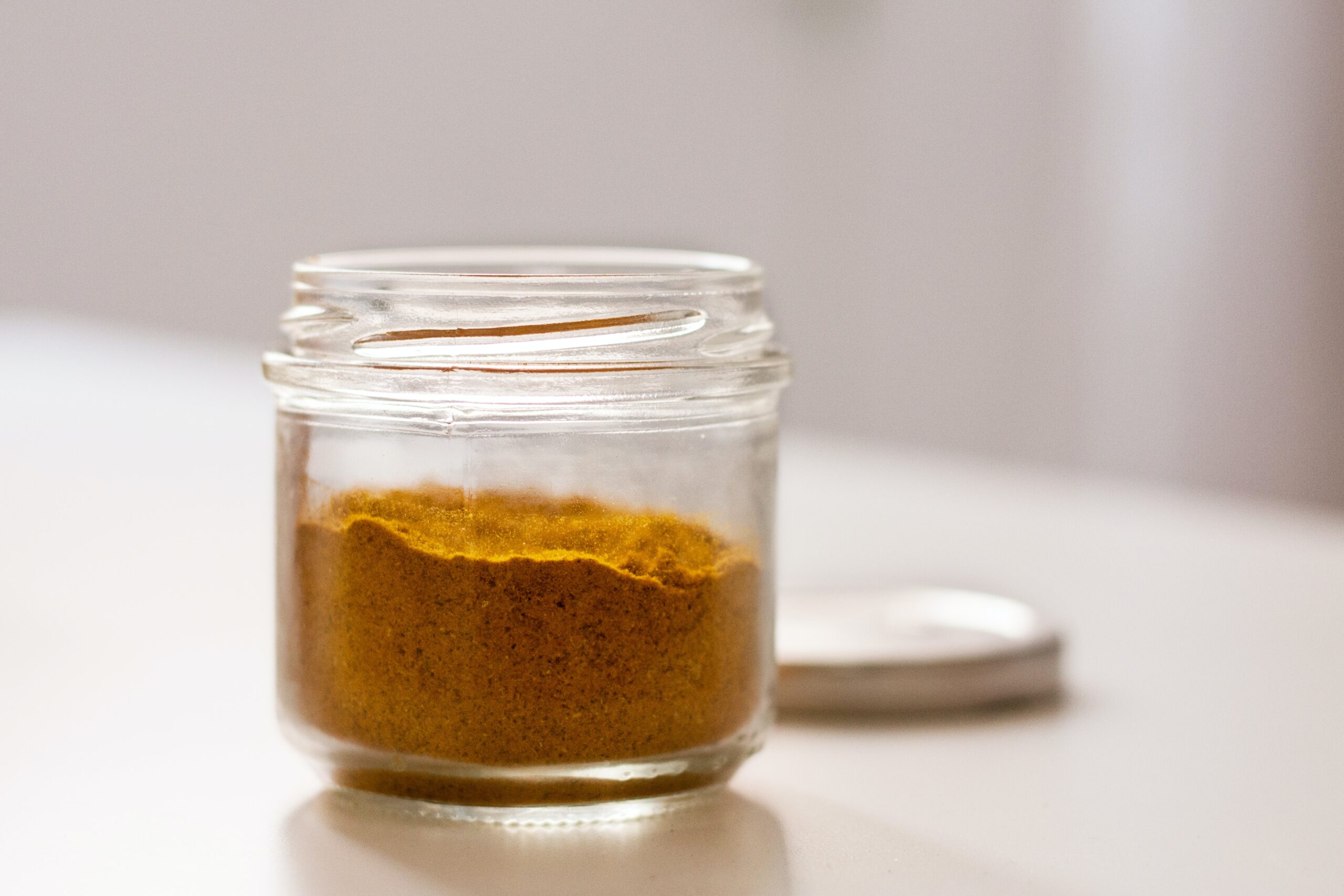 An opened jar of turmeric spice