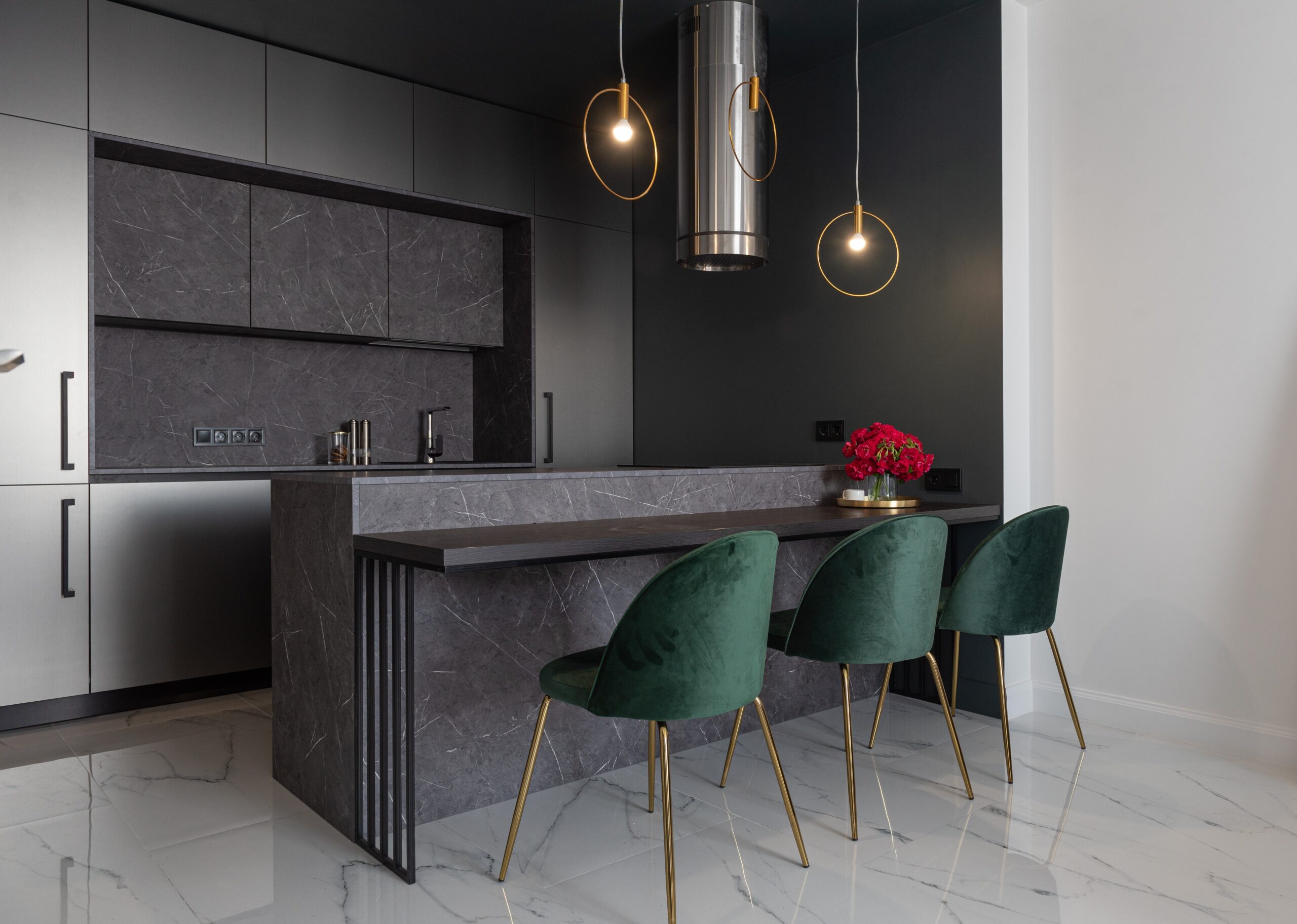 Dark forest green pairs well with matte black kitchen countertops. Pictured: Black kitchen countertops with green furniture with gold detailing.