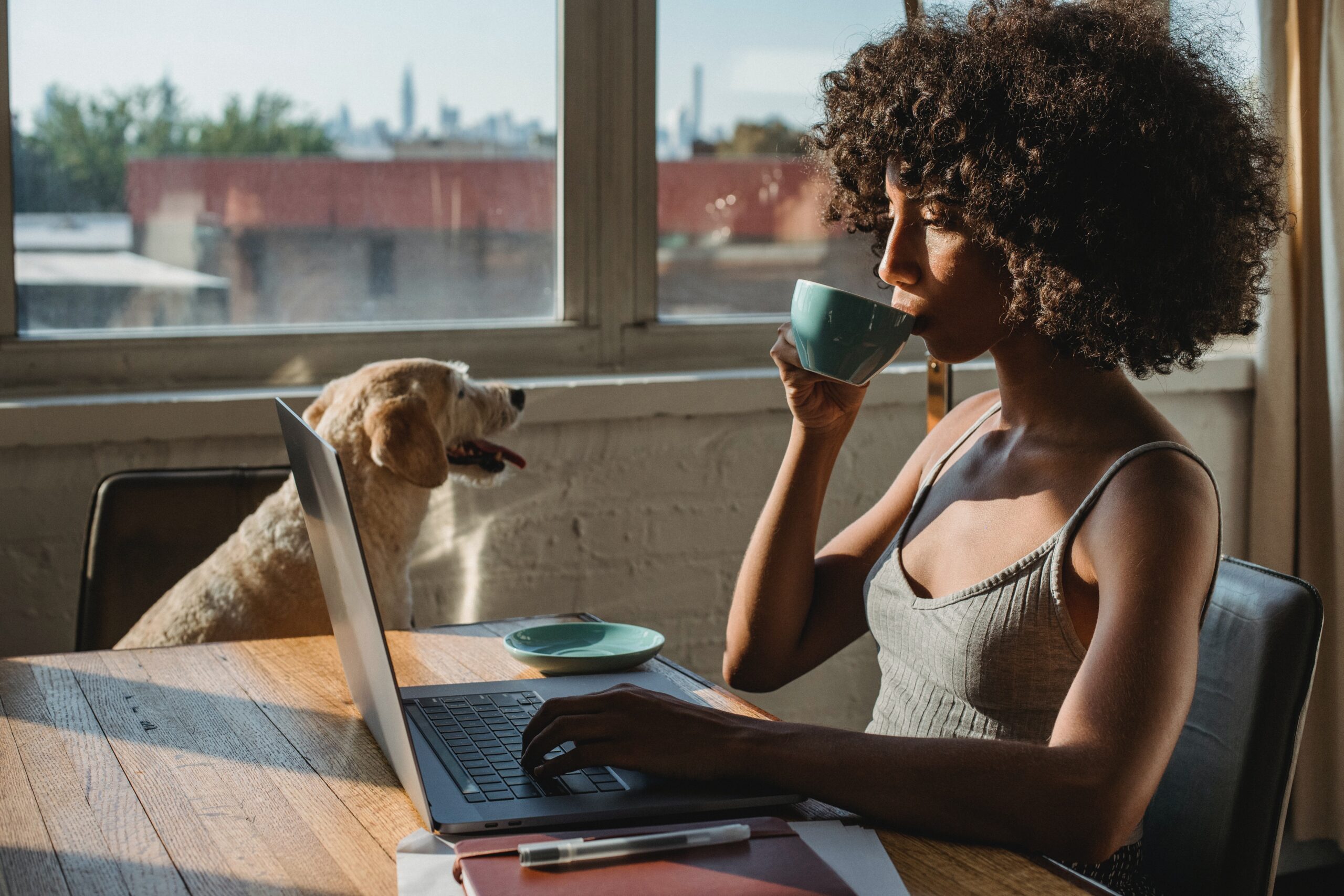 woman drinking coffee with dog nearby