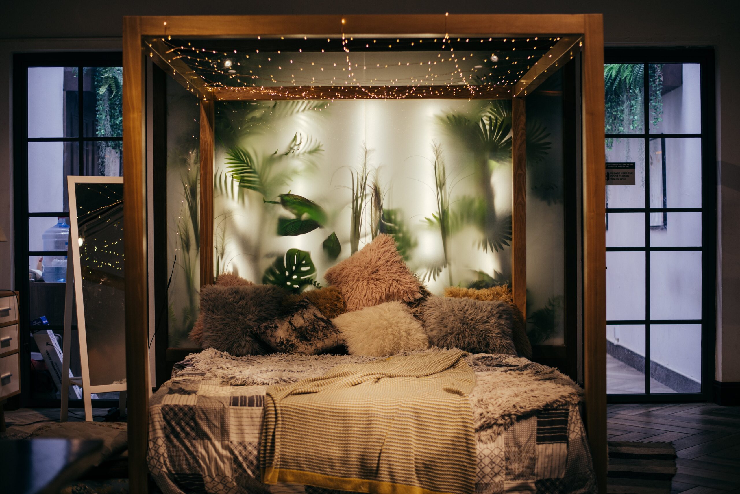 Turn your hobo bedroom into a tropical oasis with leaves, flamingo decor, and shades of green. Pictured: A boho bedroom with tropical leaves in the background.