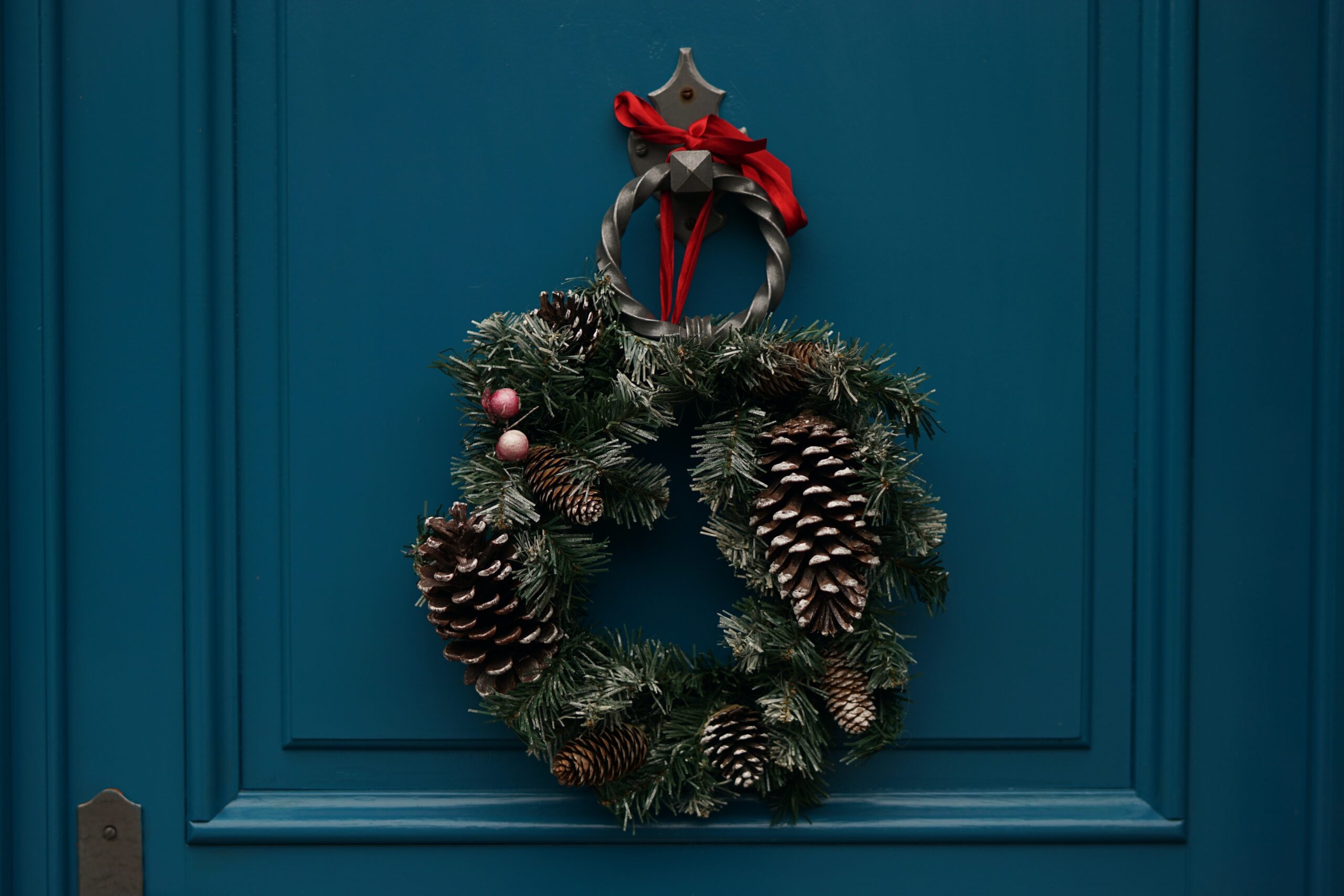 A holiday wreath hanging on a blue door