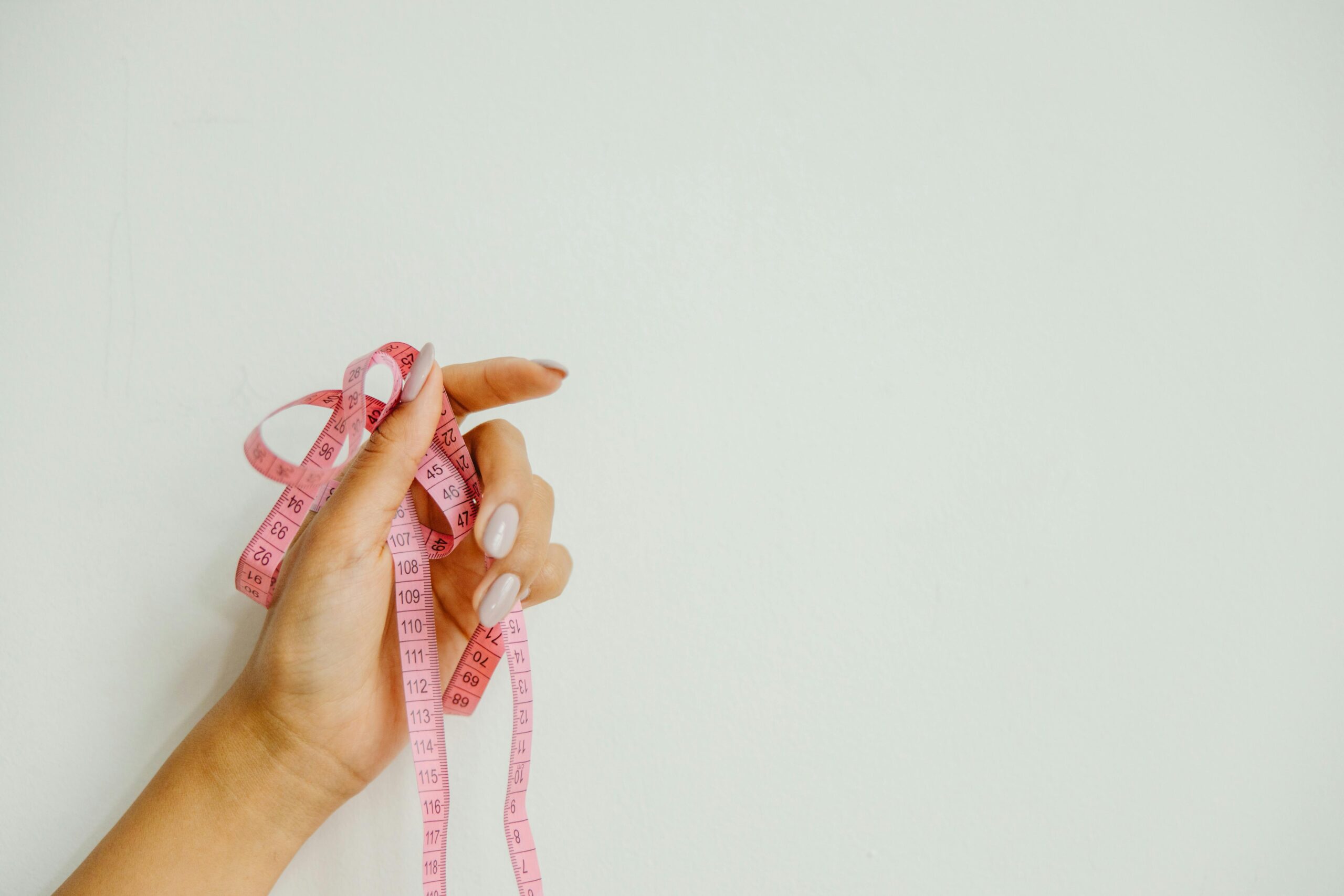 A hand holding pink measuring tape