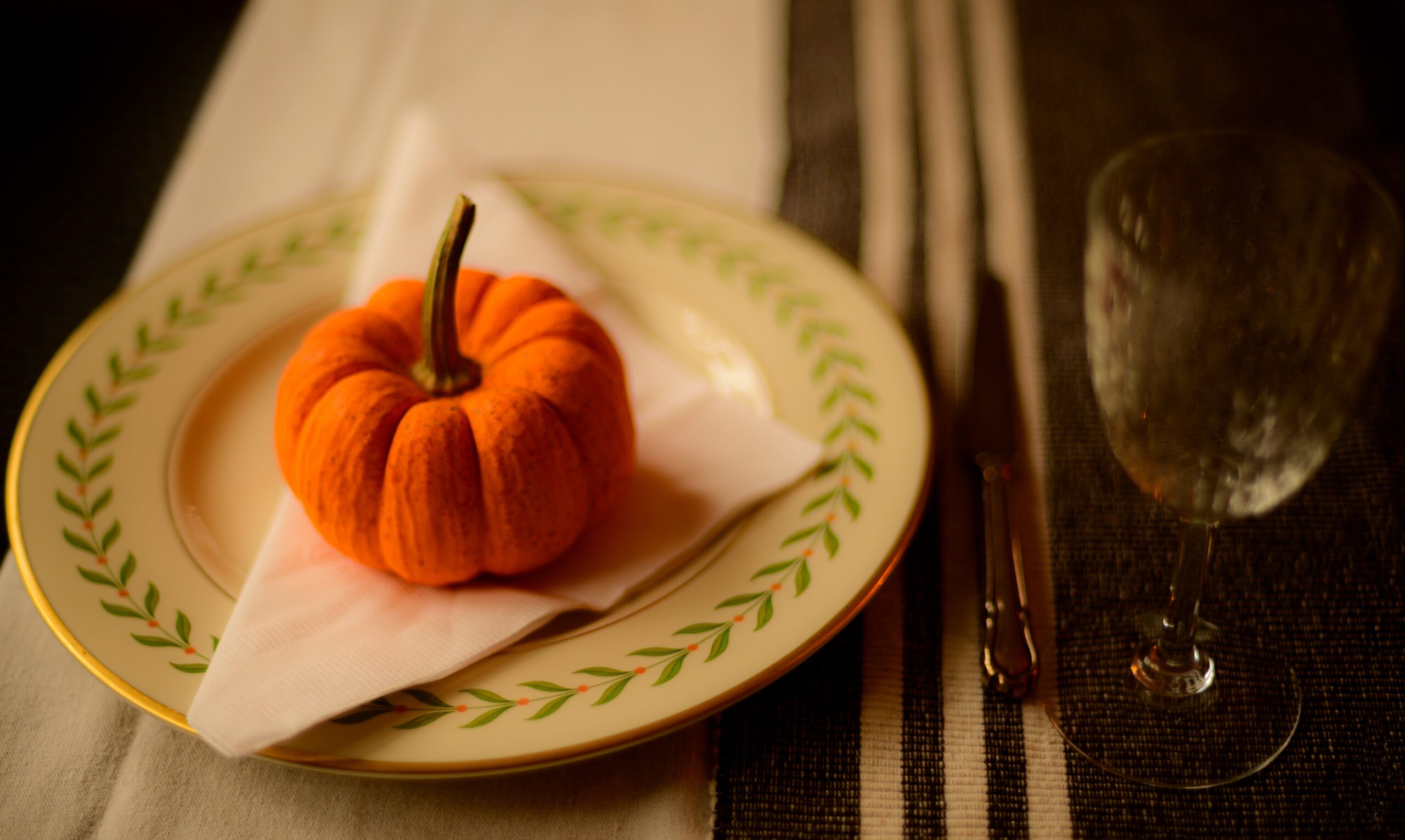 Decorate your home for friendsgiving using the tablescape idea and Thanksgiving decor and colors. Pictured: A Thanksgiving themed tablescape with pumpkin decor.