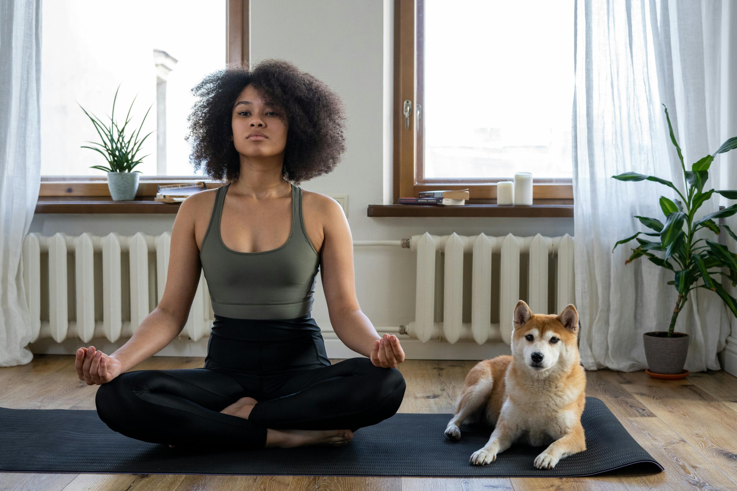 A woman practicing yoga with her dog by her side