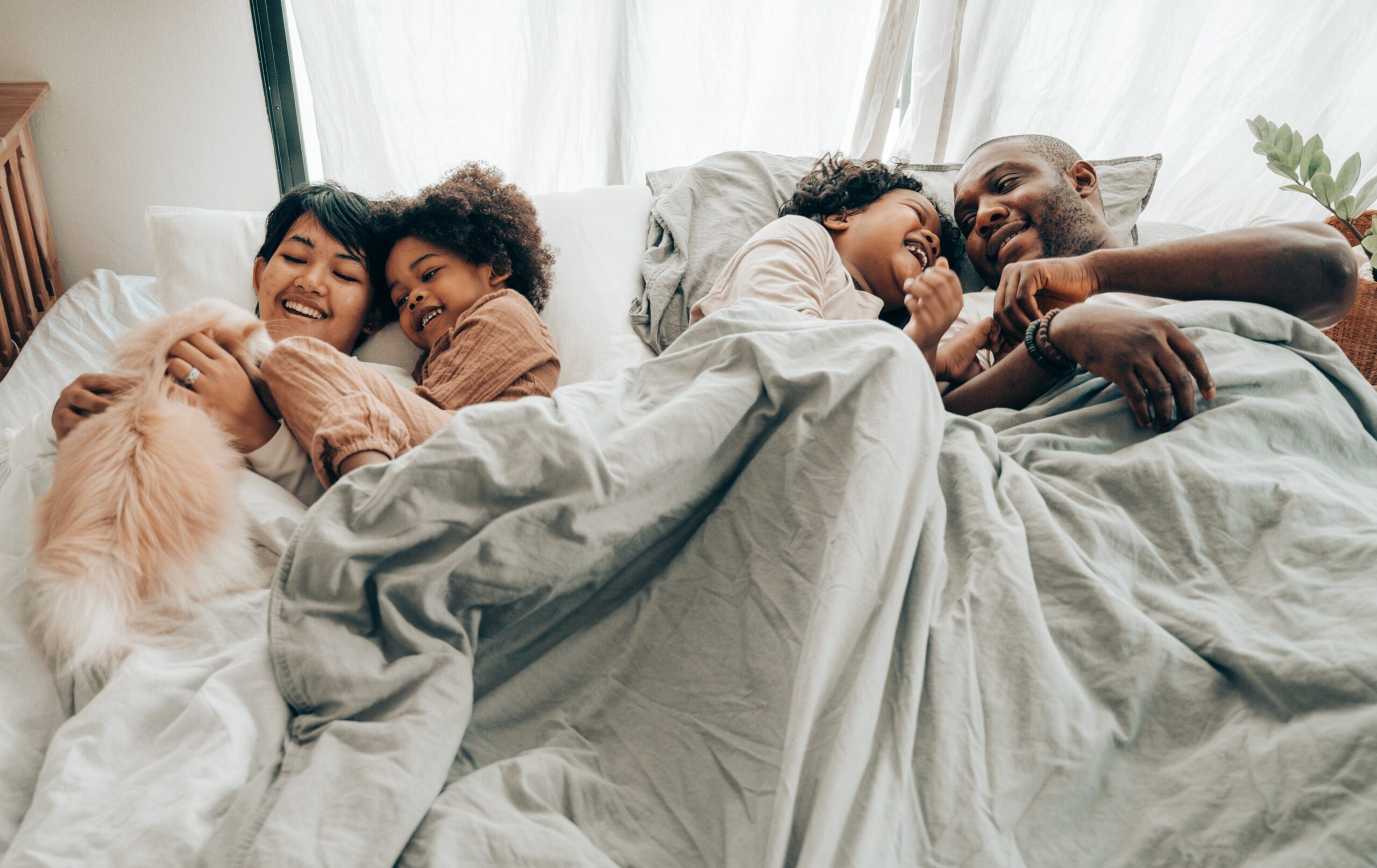family in bed with bedsheets