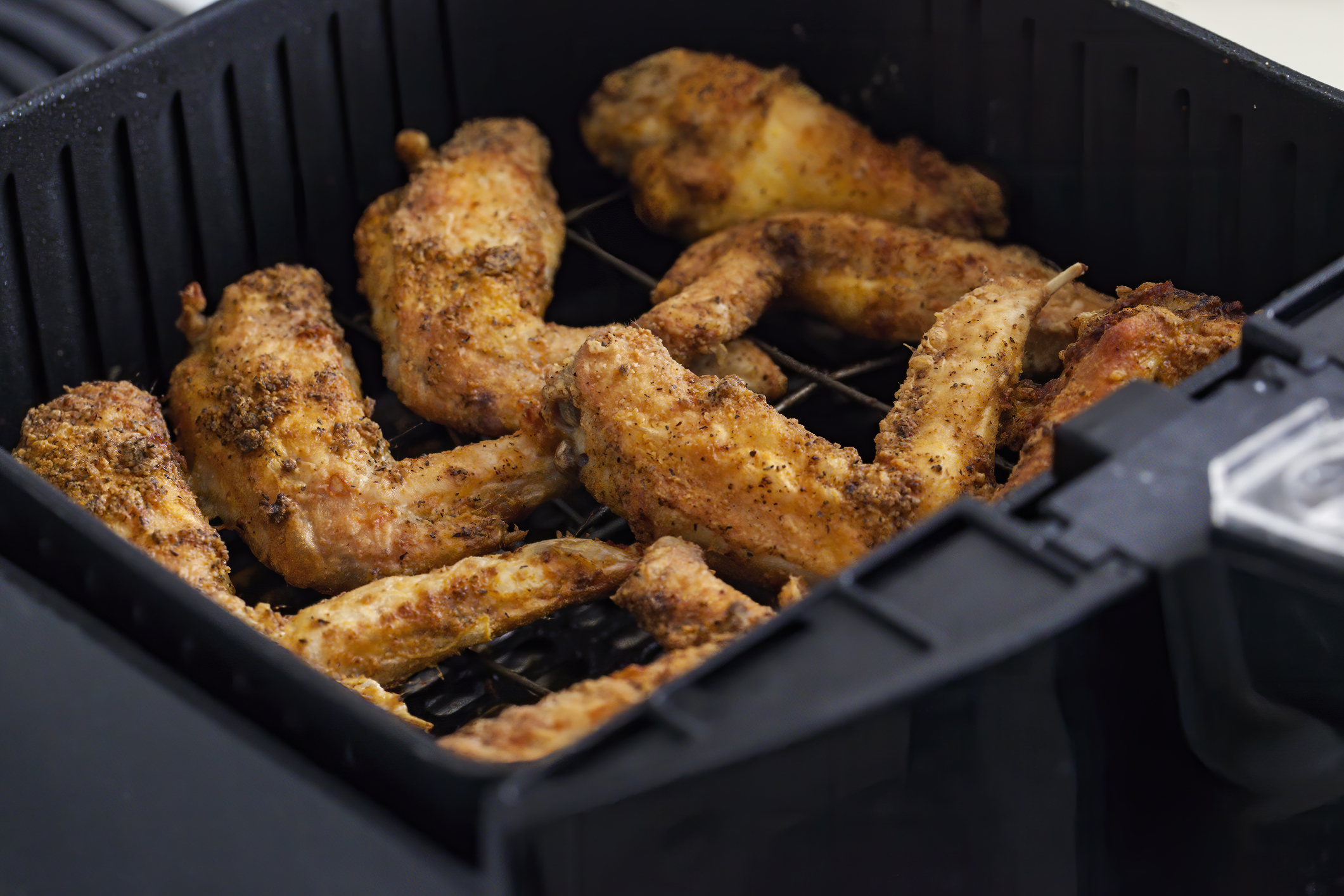 Here's how to clean grease and stuck on gunk in your air fryer. Pictured: An air fryer with fully cooked chicken in the basket
