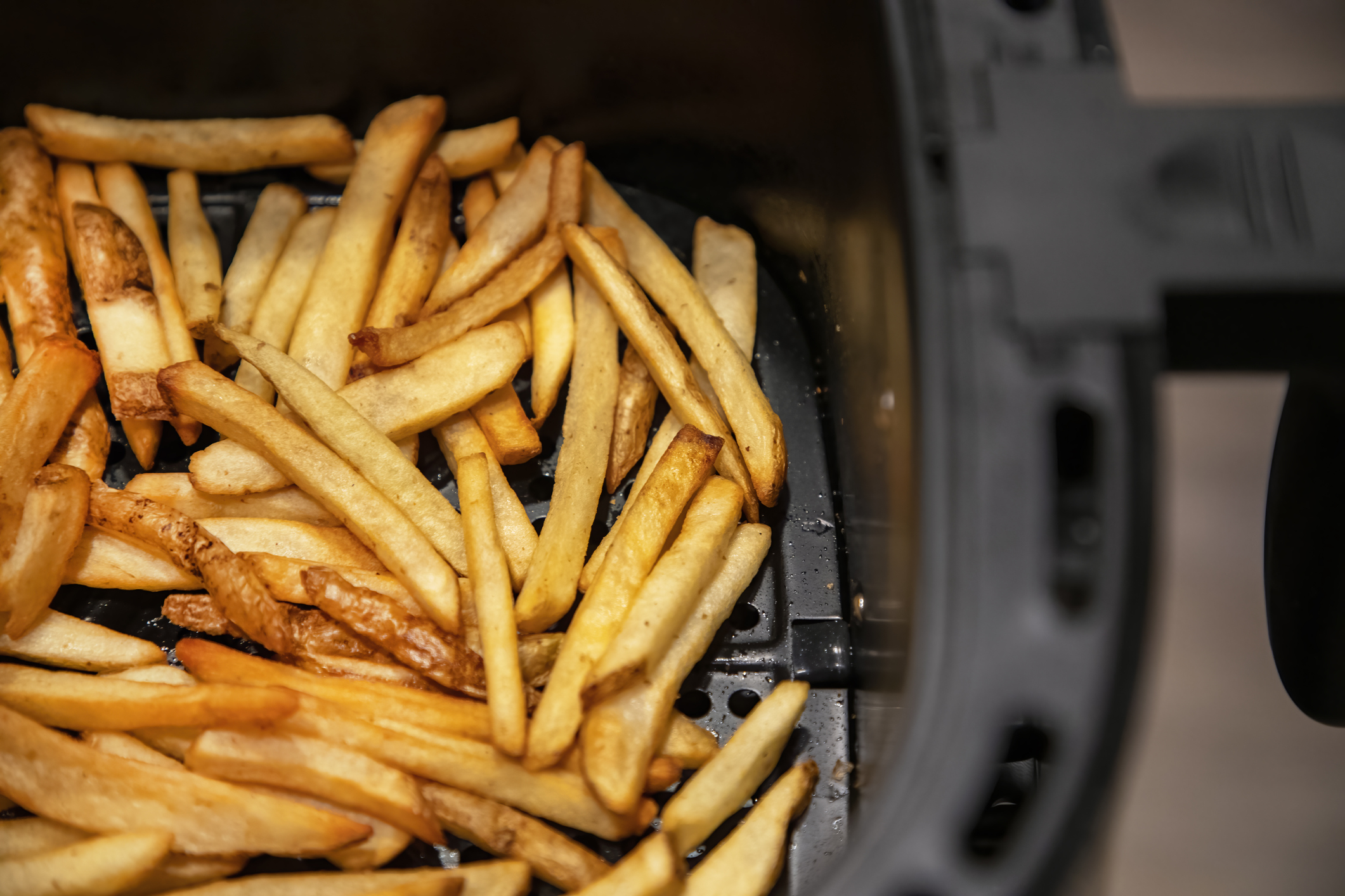 This step-by-step guide shows you how to clean an air fryer. Pictured: An air fryer with fries in the basket