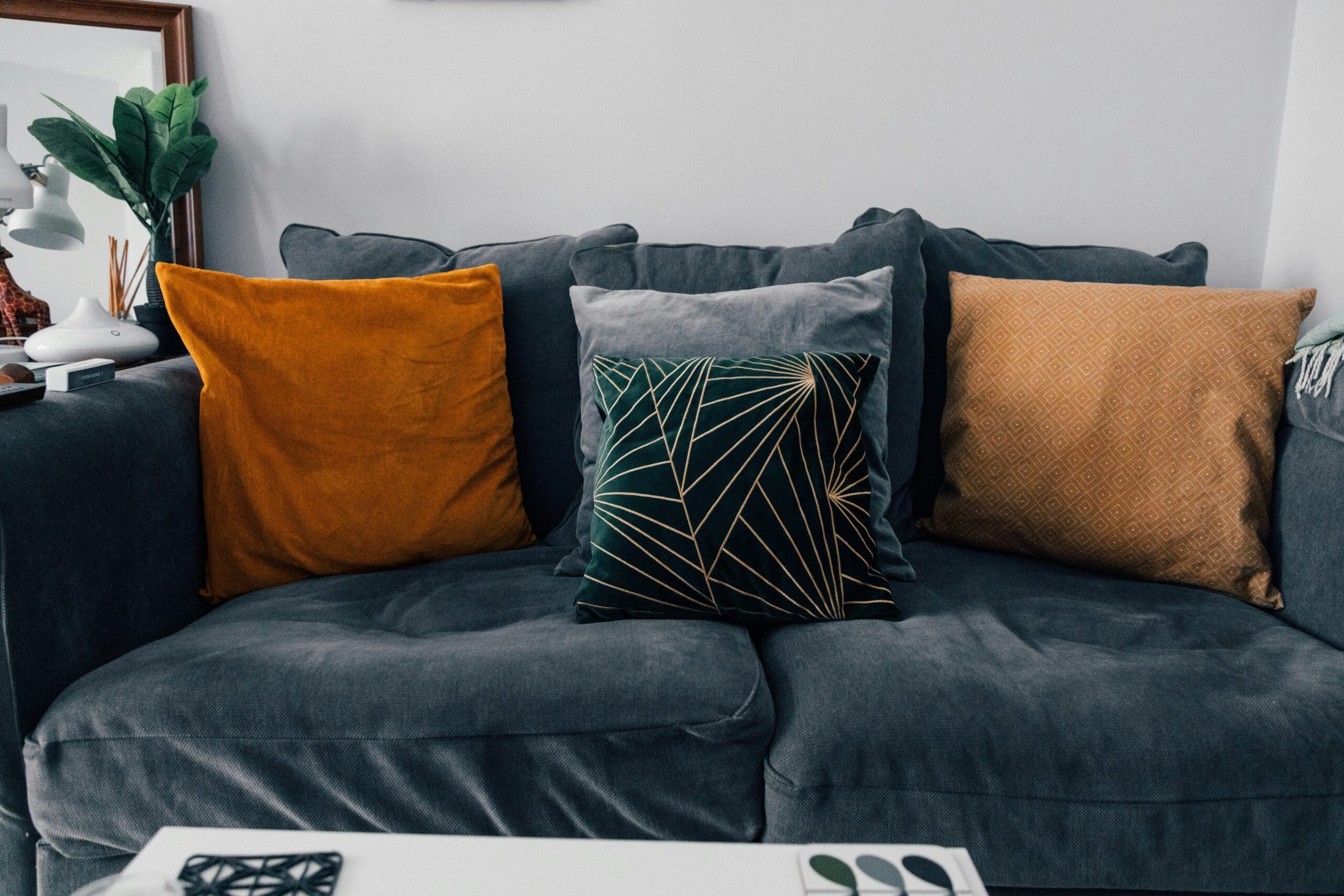 If you want to learn how to clean a velvet couch, here are a few simple steps and things you'll need. Pictured: A blue velvet couch with decorative pillows