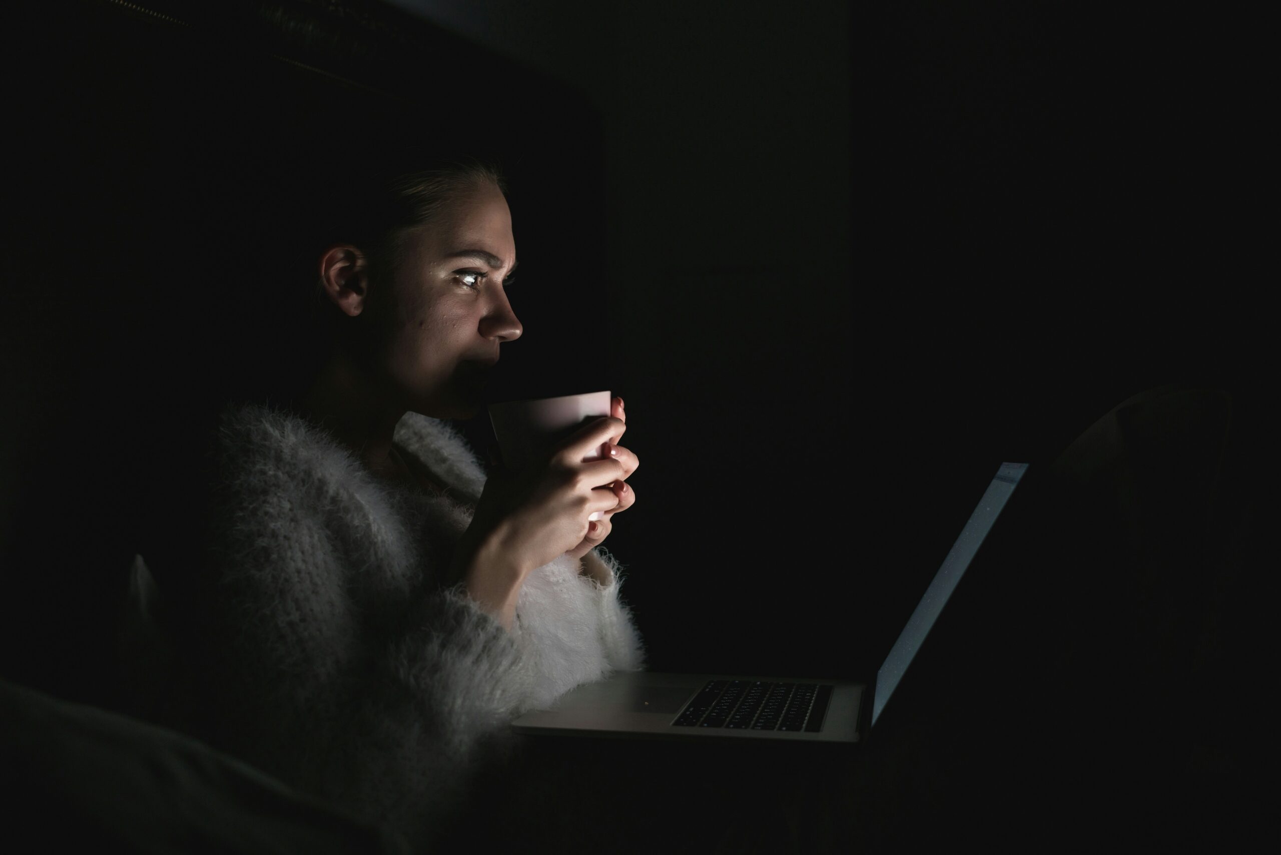 A woman browsing on her laptop while in bed