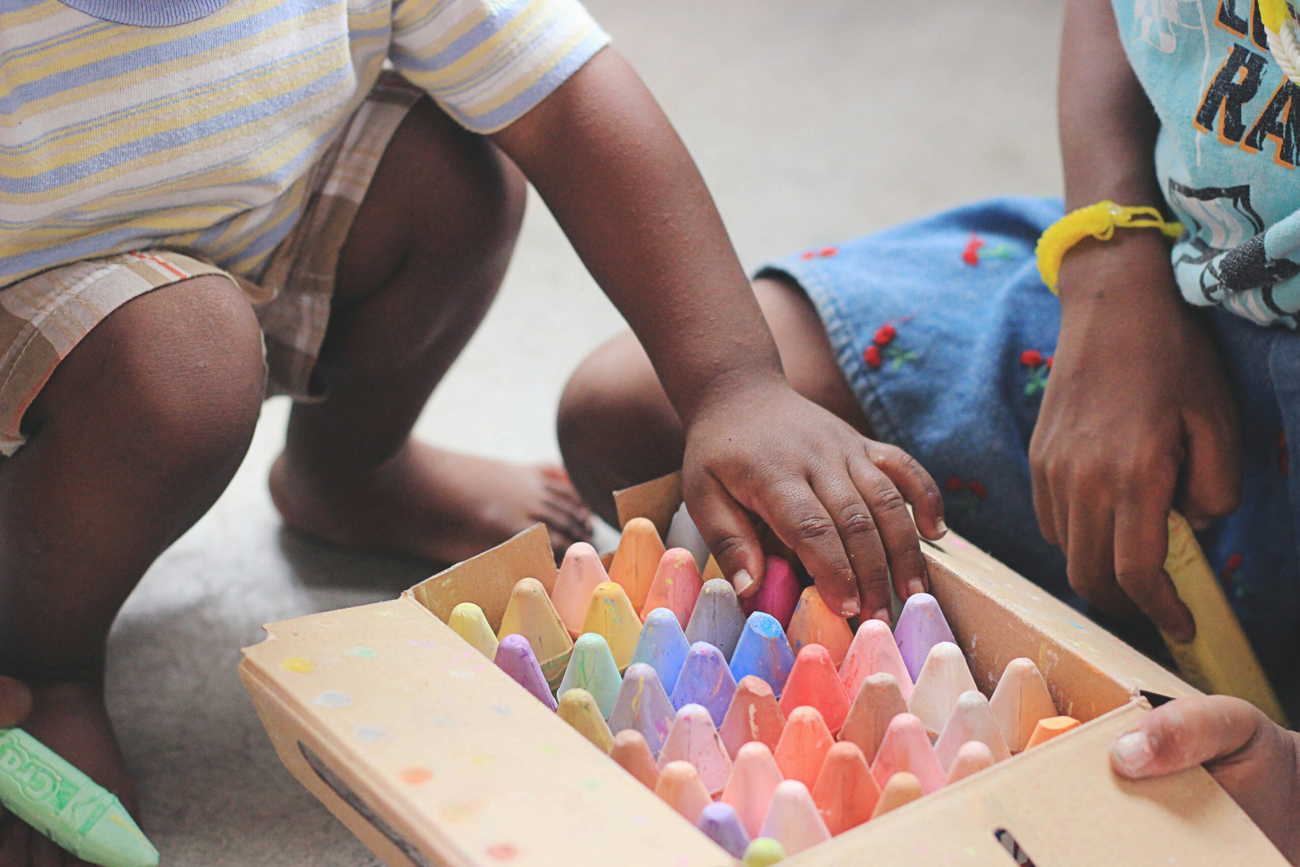 A child putting away chalk with their parent