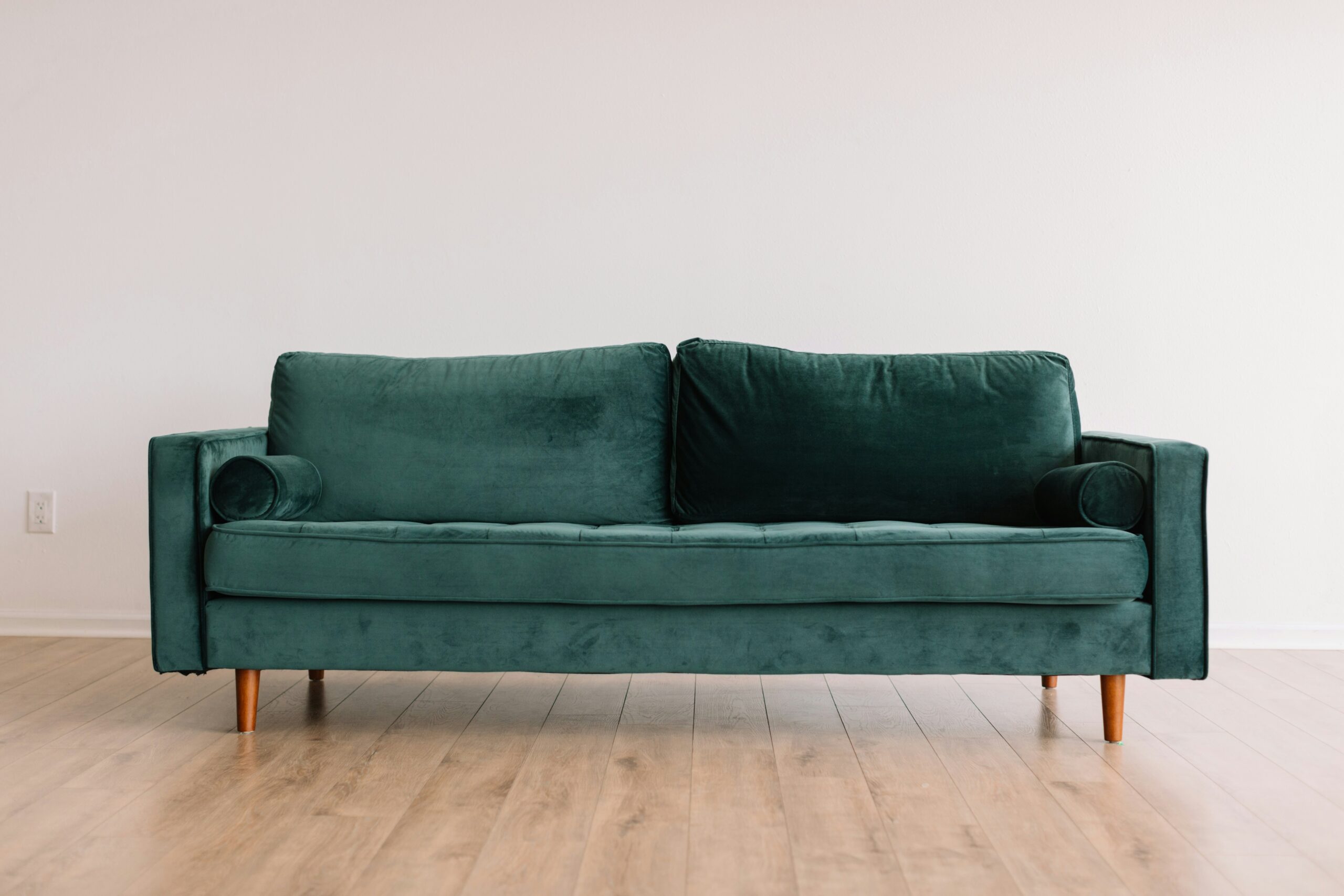 To incorporate a triadic color scheme in your home, utilize shades of green, violet and orange. Pictured: A green velvet couch