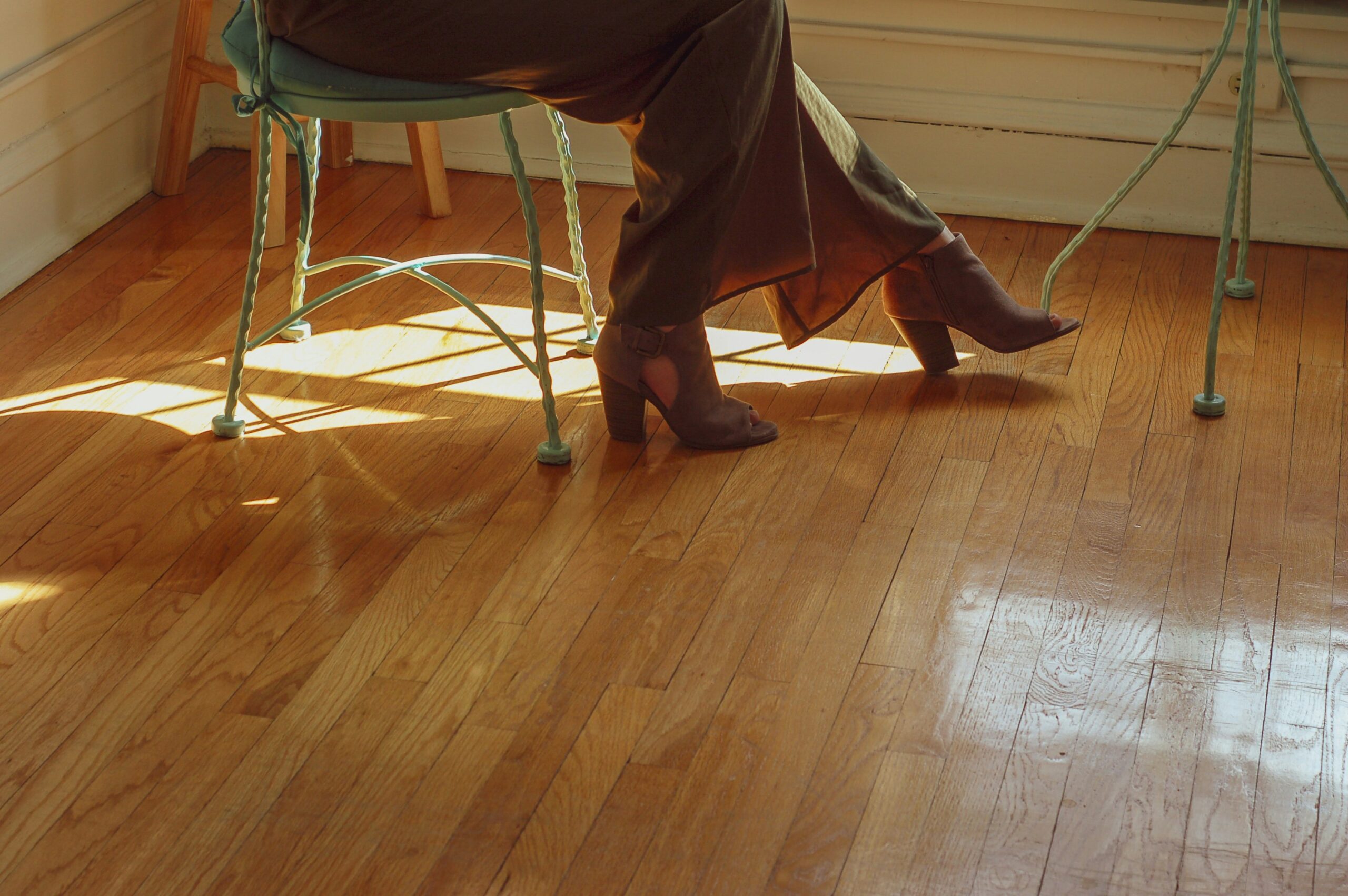 A close up of a woman's heel boots on hardwood floor