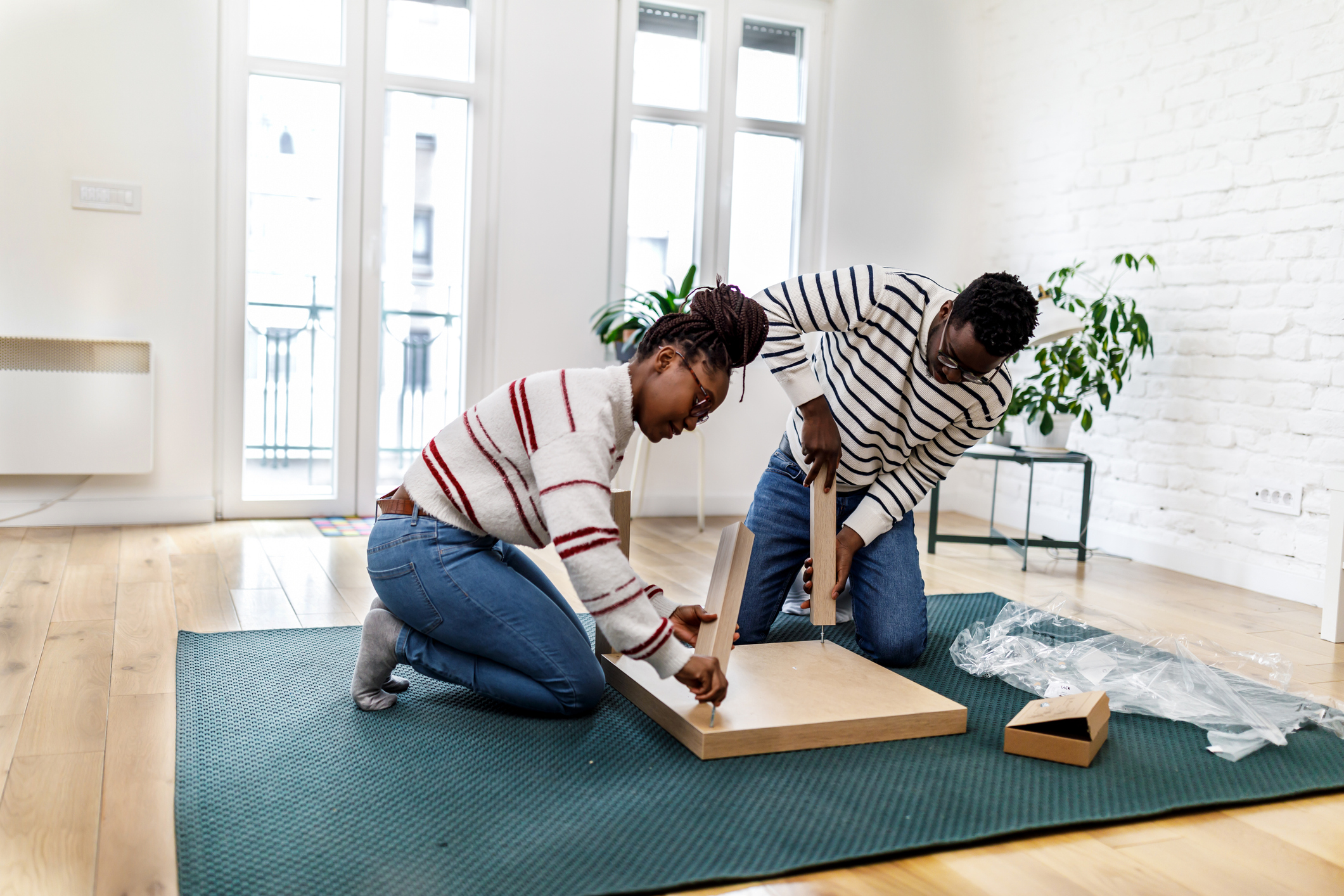 A young couple of Afro-Americans is assembling new furniture in their house. how to get furniture for cheap in your new home