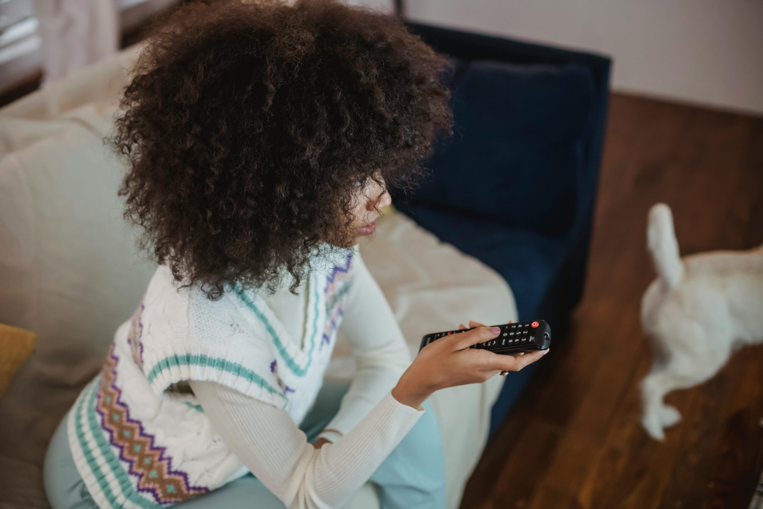A woman watching tv while holding a remote control