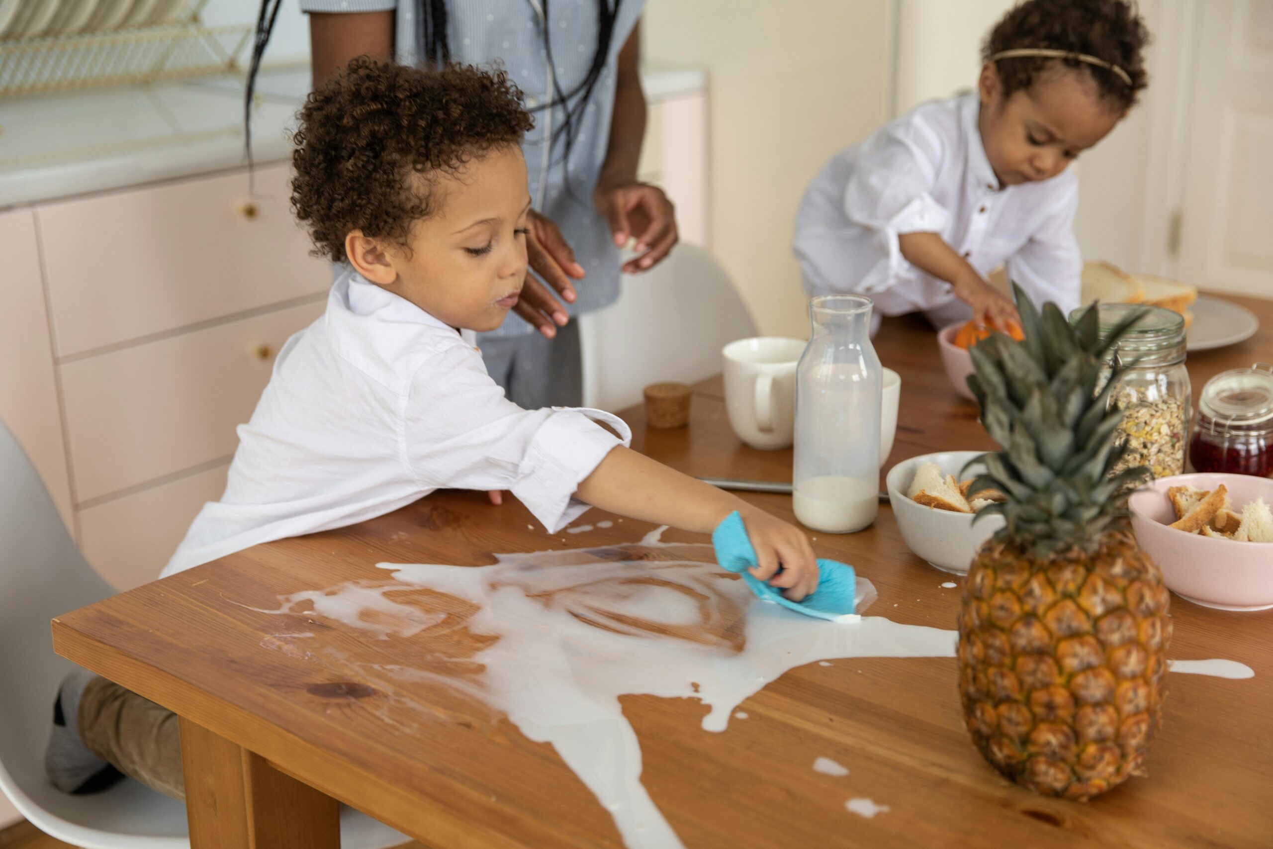 Kids spilling milk on a kitchen countertop