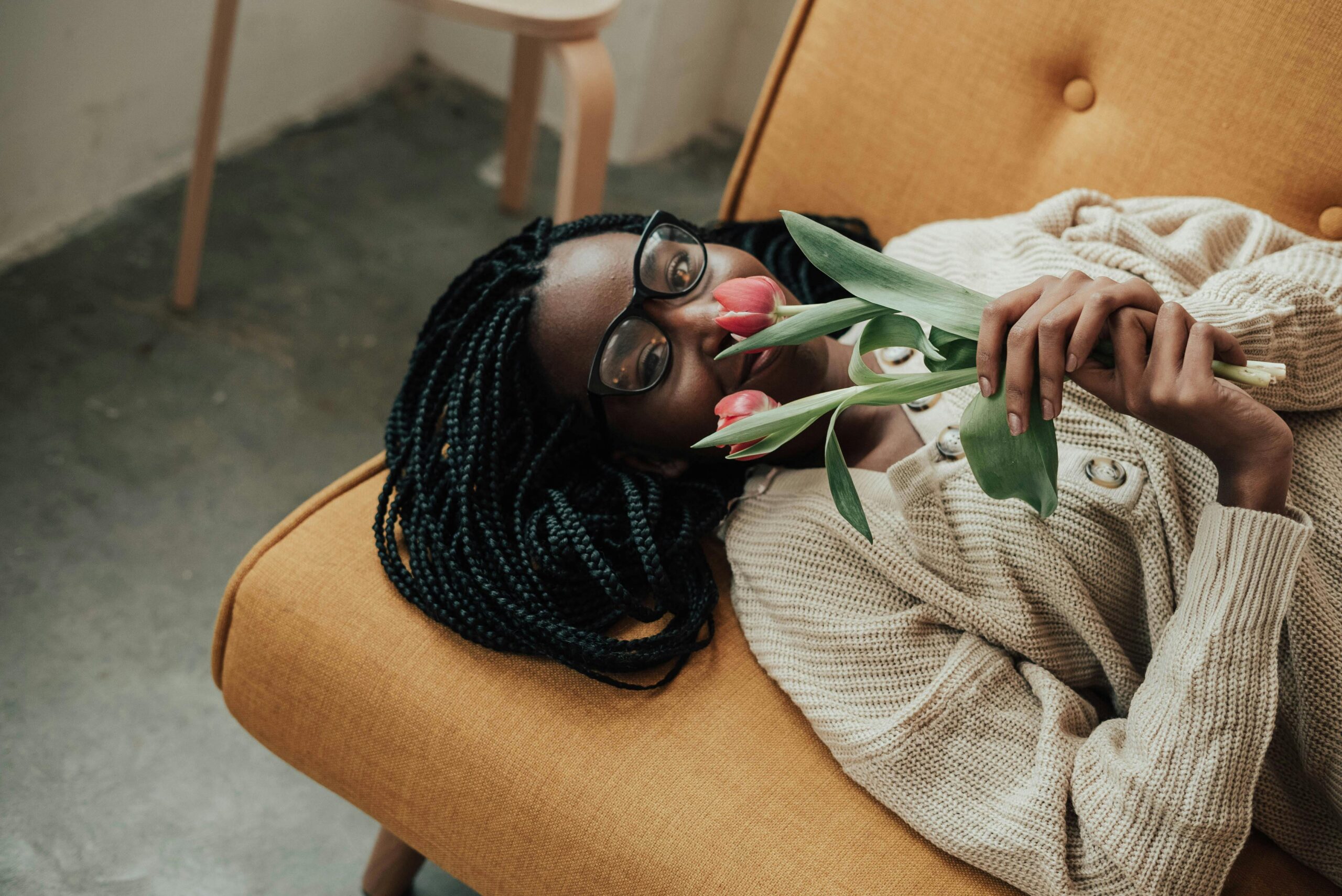 A woman holding red tulips while laying on a couch