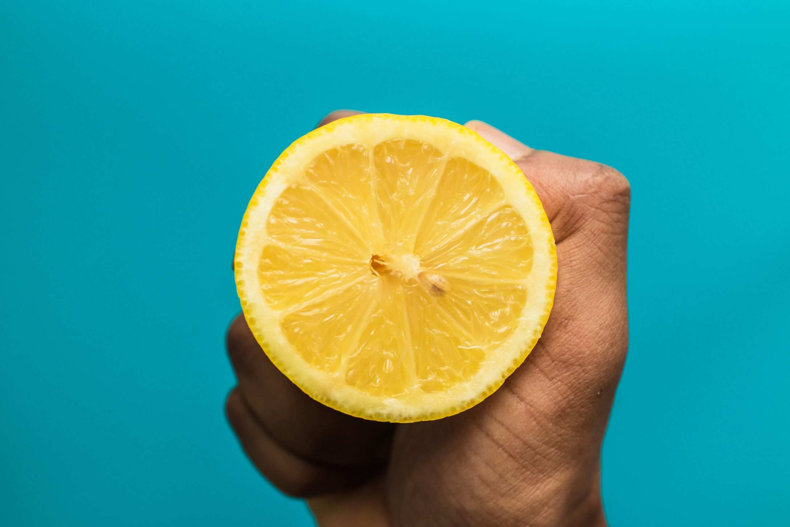 A hand squeezing a lemon half