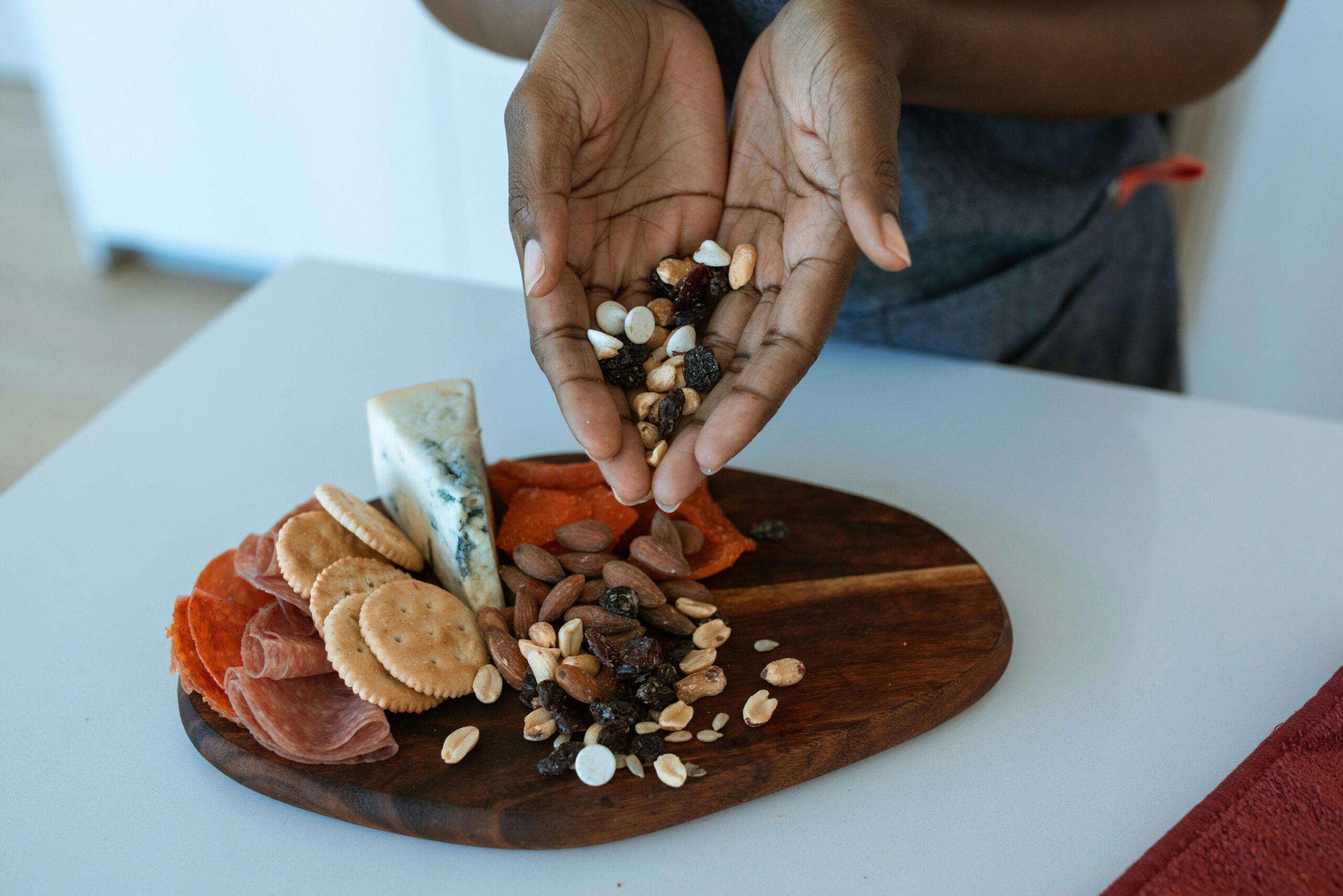 A woman putting trail mix on a charcuterie board