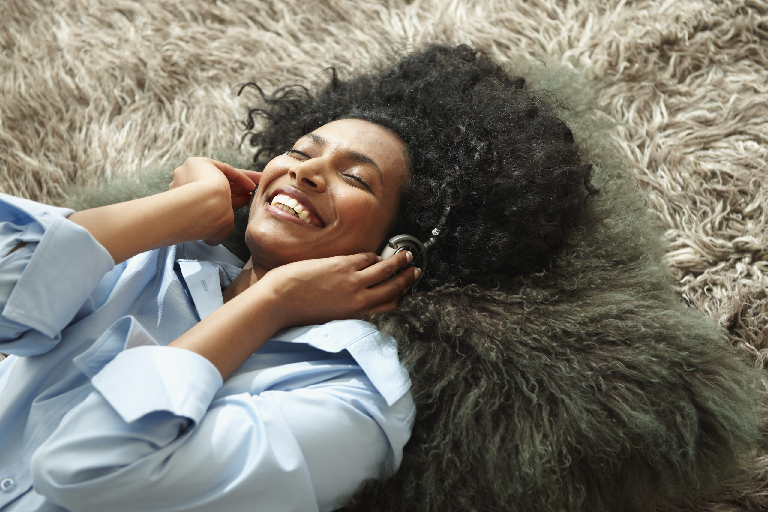 woman enjoying music while laying on shag rug