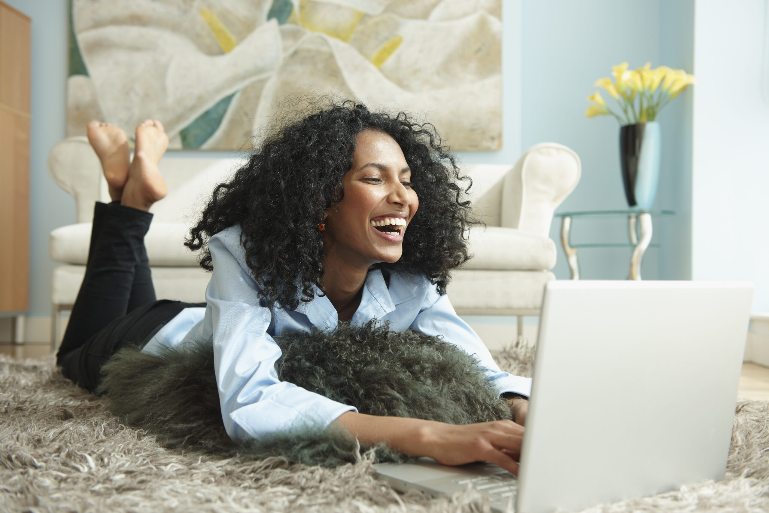 woman lays on shag rug while doing work