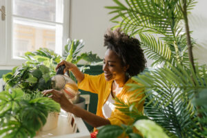 how to protect garden in extreme heat Pictured: A black woman watering her garden