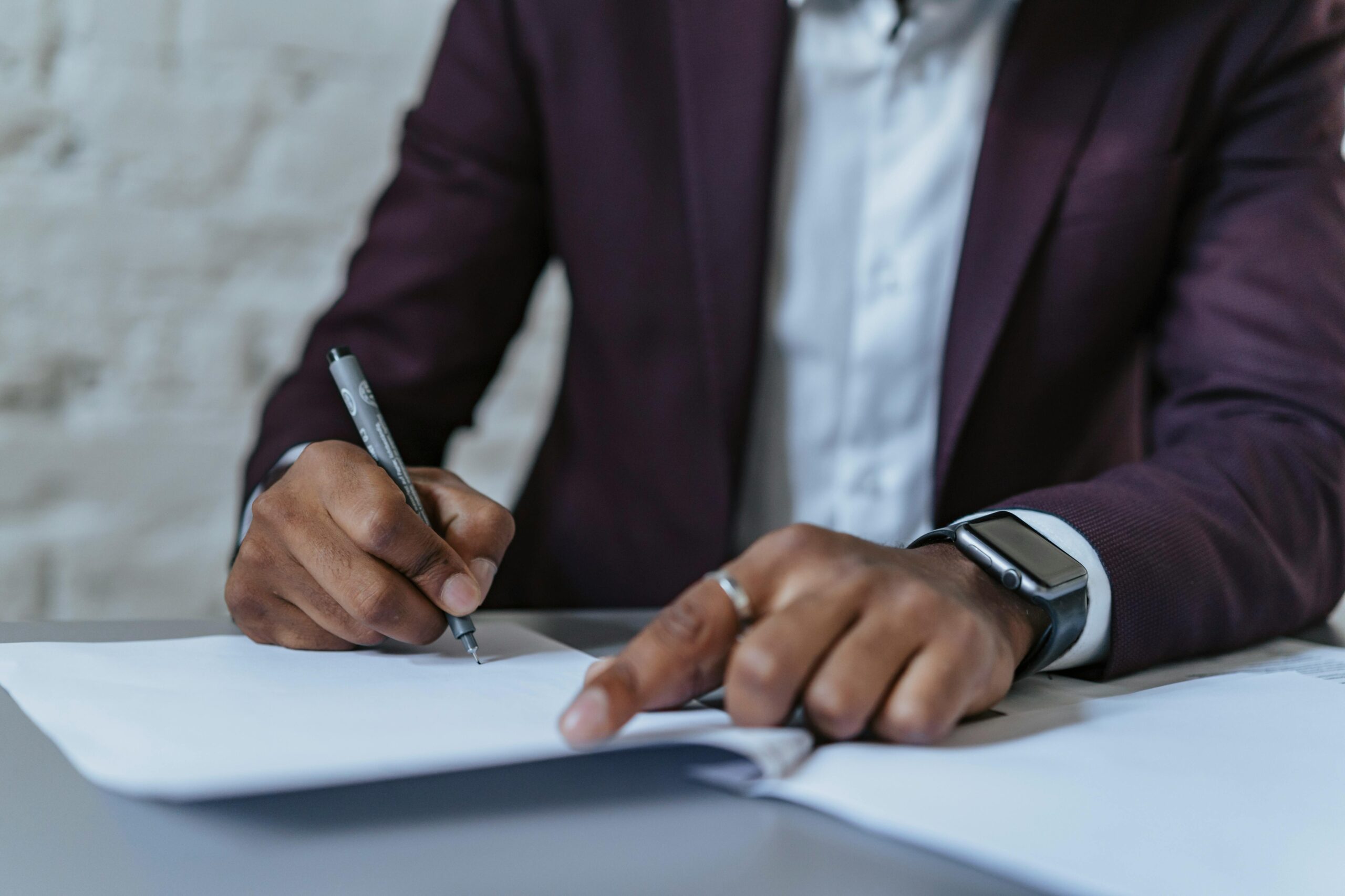 A cropped man in a suit signing a contract