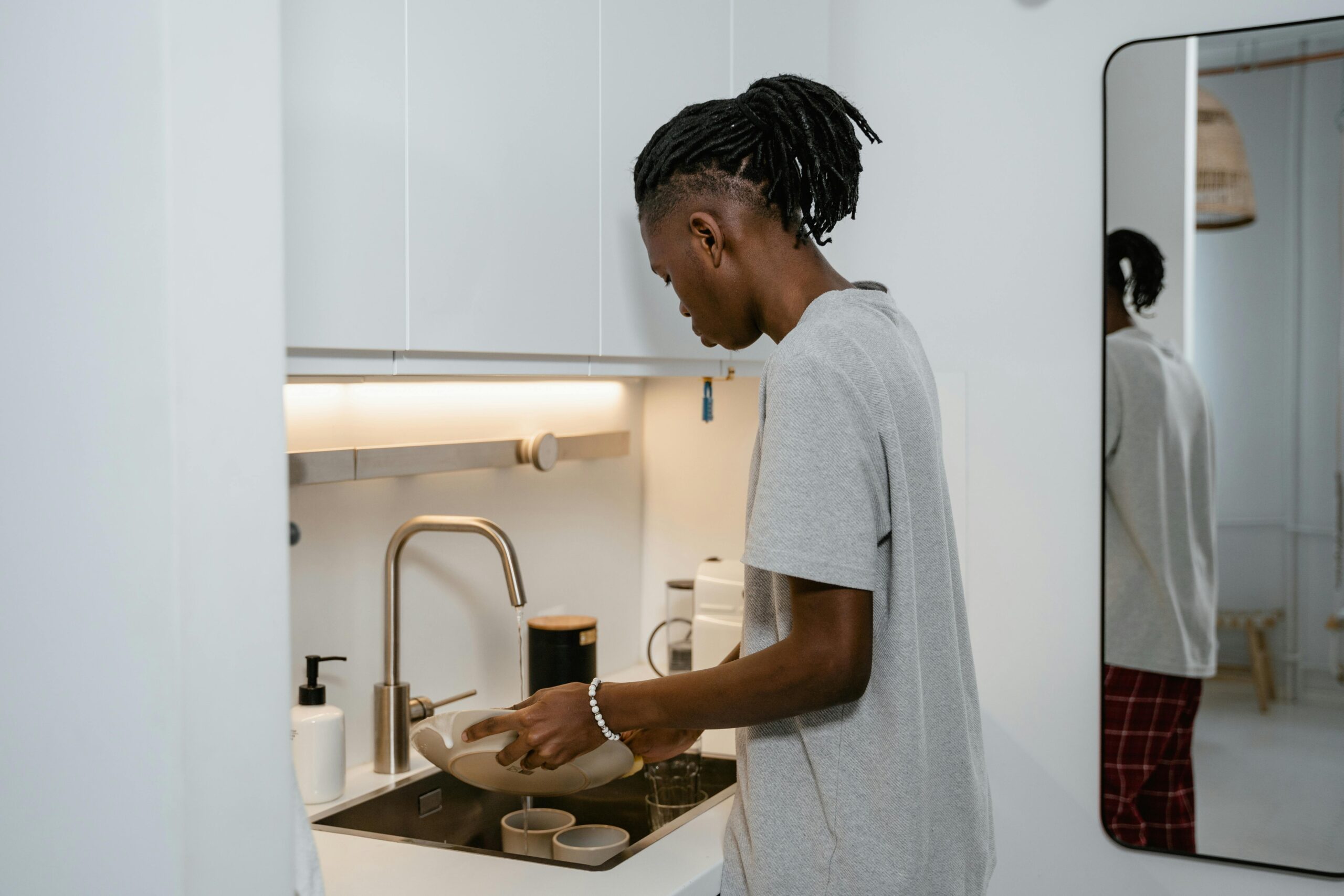 A man rinsing a dish in the sink