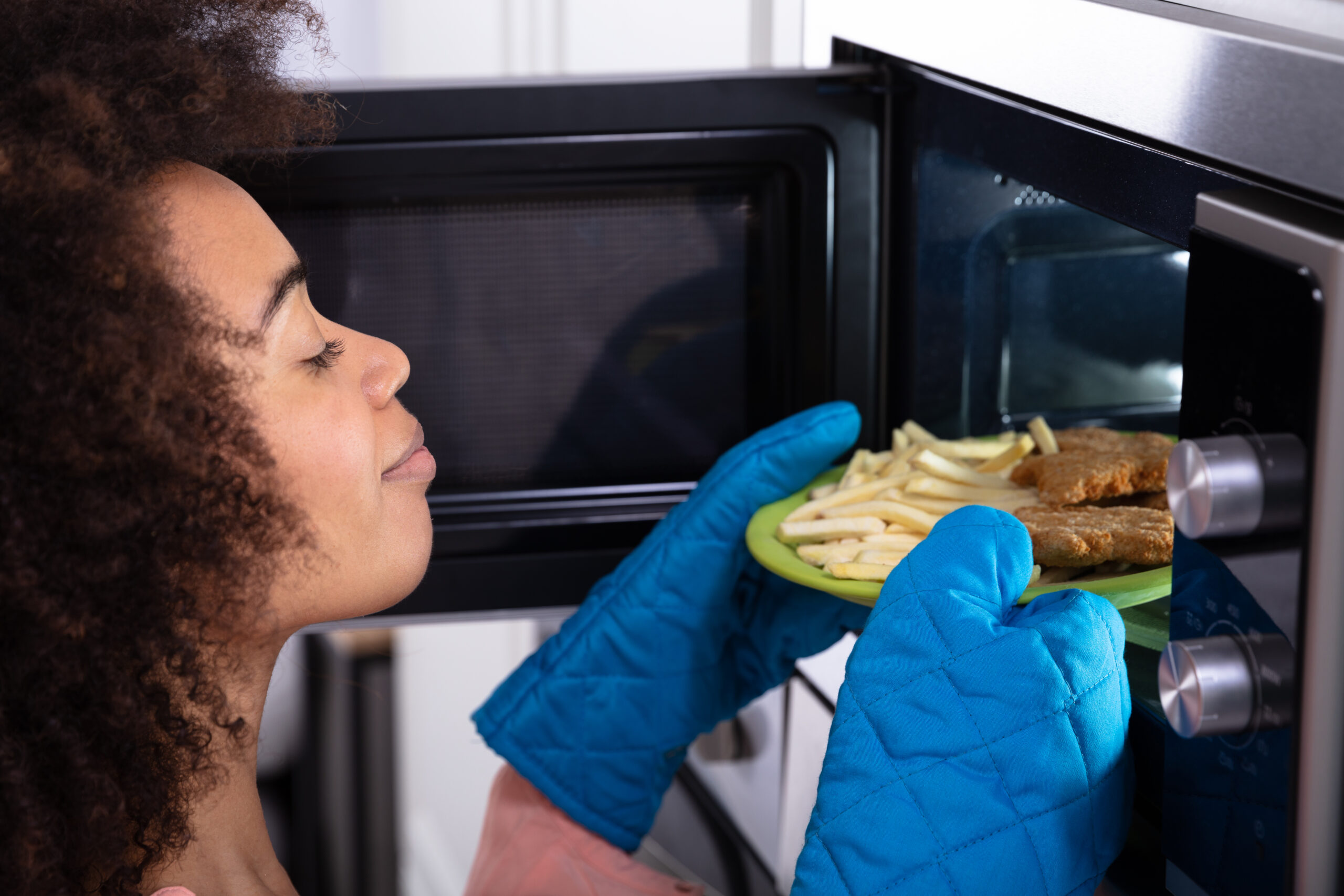 woman putting items in microwave