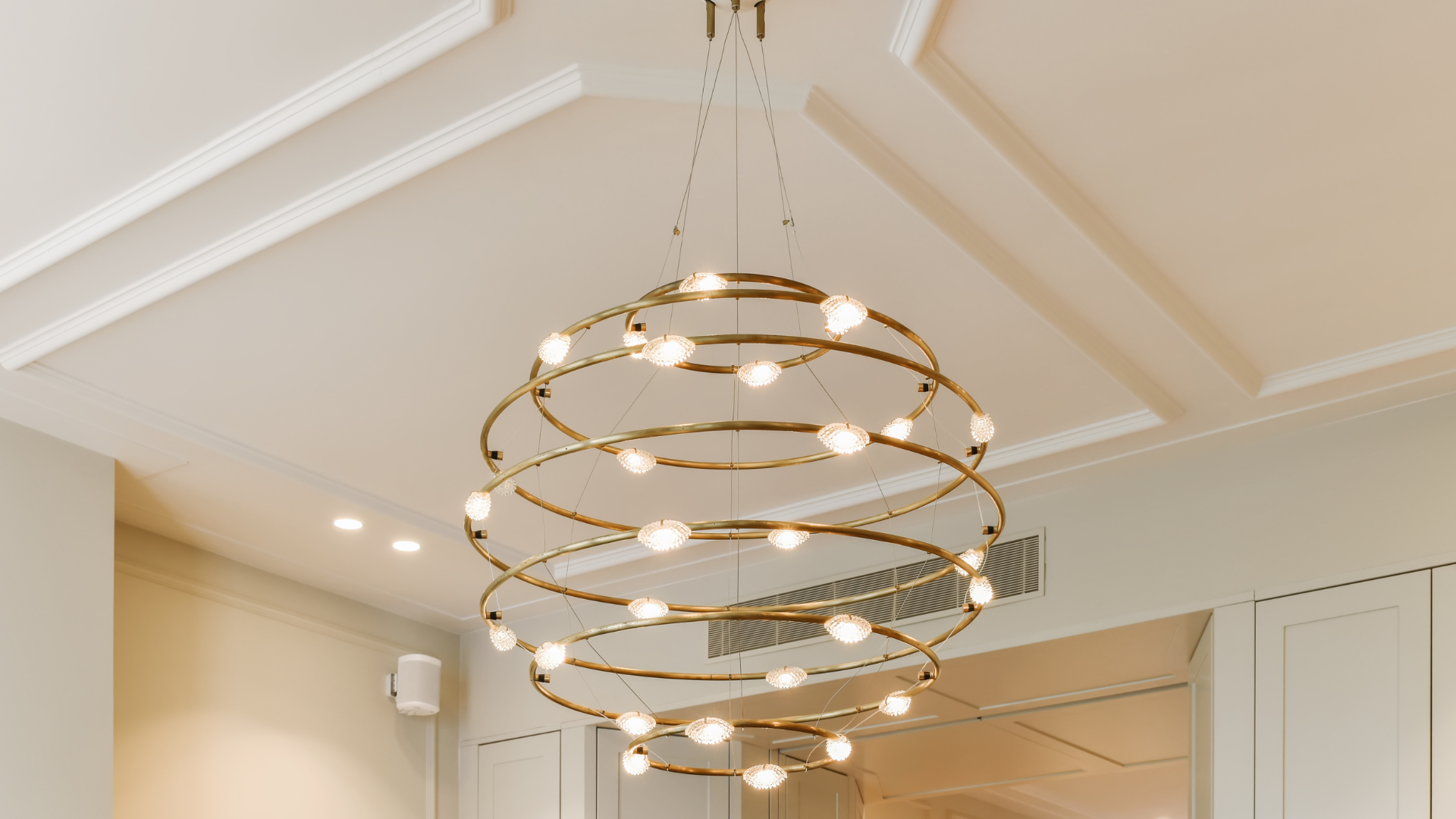 Circular pendant chandelier hanging from white ceiling