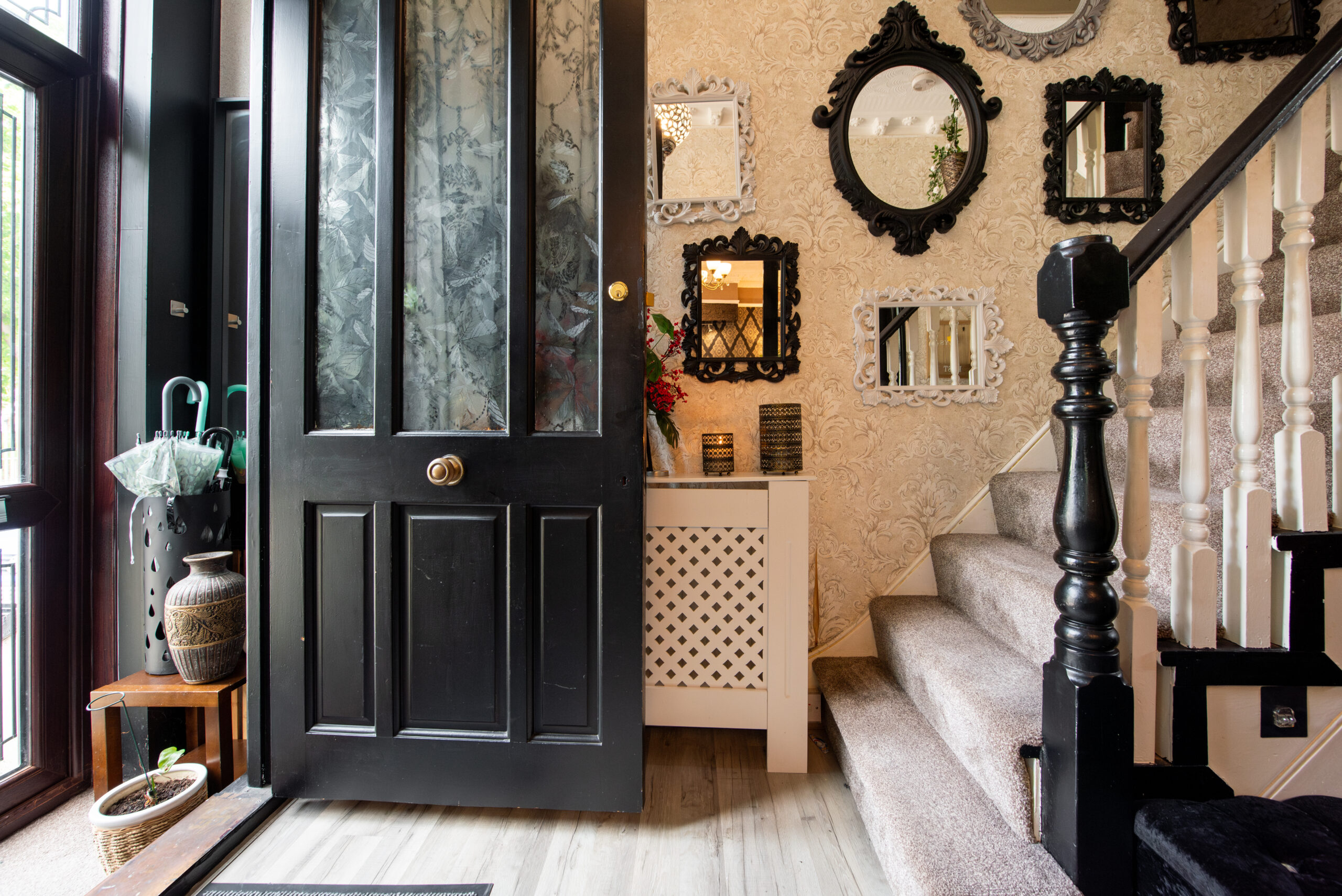 A general interior view of a hallway with staircase and multiple various antique mirrors