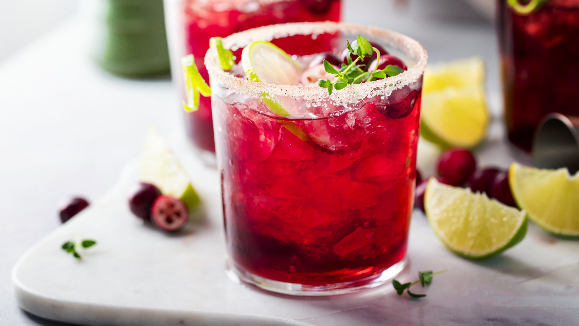 Sangrita brunch cocktail in short glass with sugared rim surrounded by fruit and limes