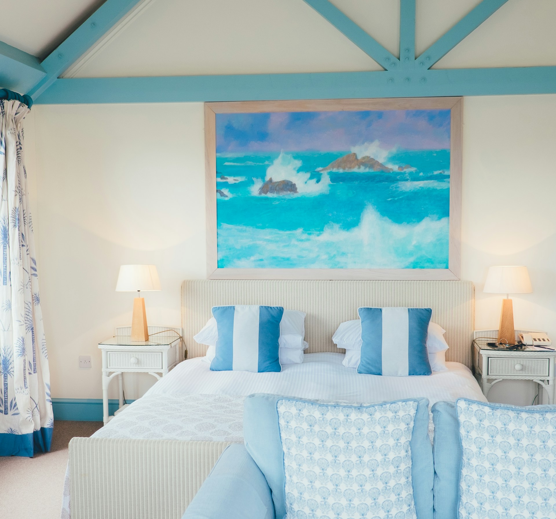 Bright blue and white room with paintings and pillows
