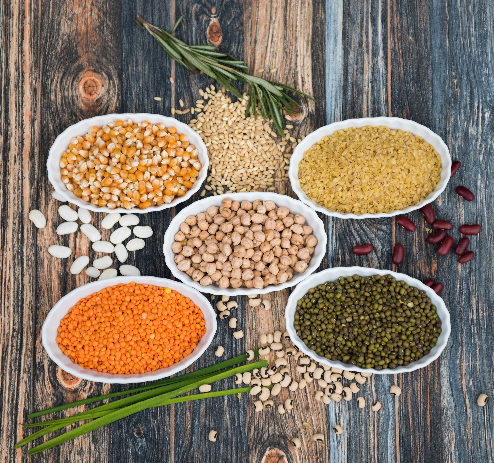 Various colors of lentil beans in white bowls
