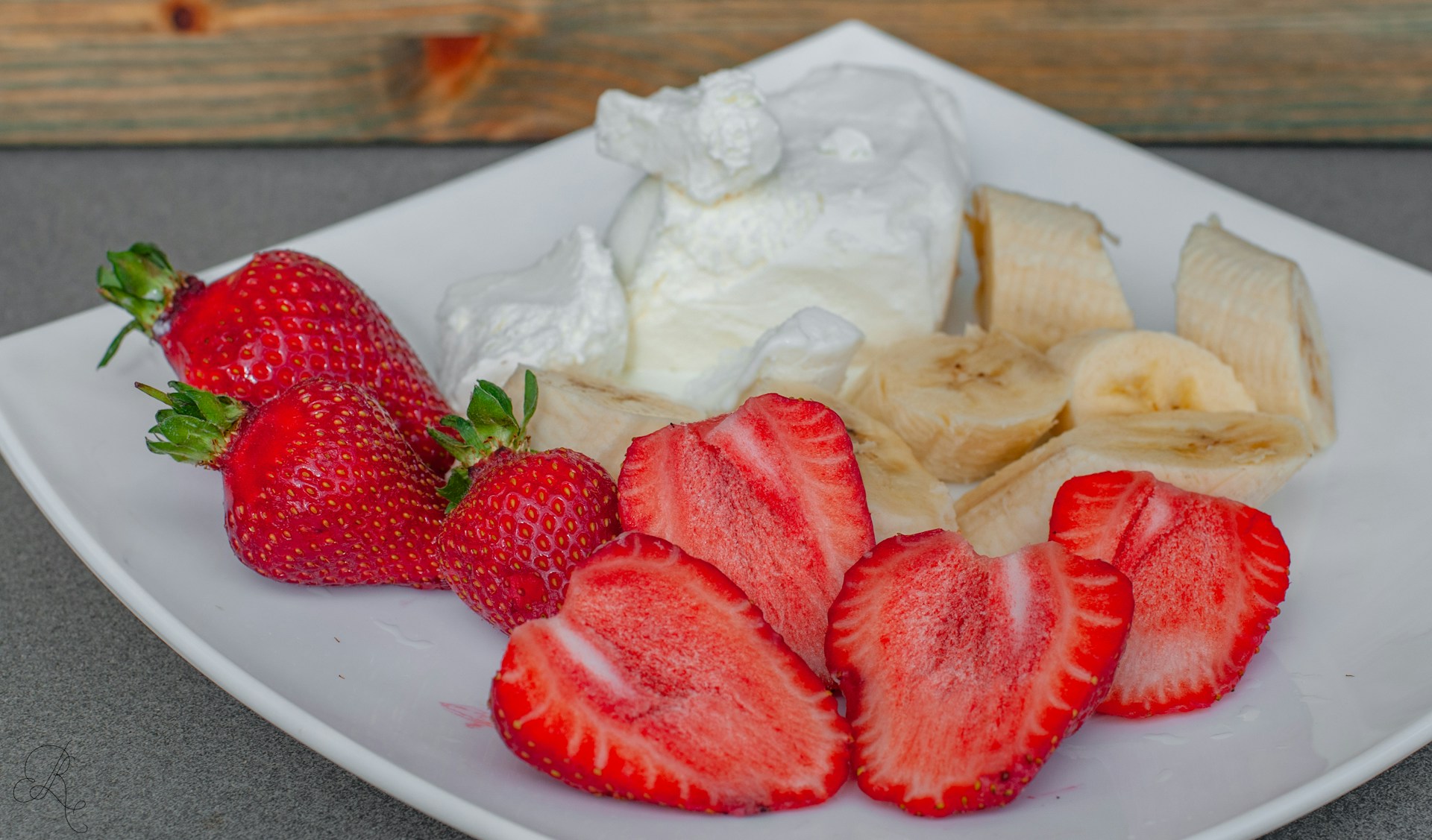 Strawberries and bananas on a plate with whipped cream
