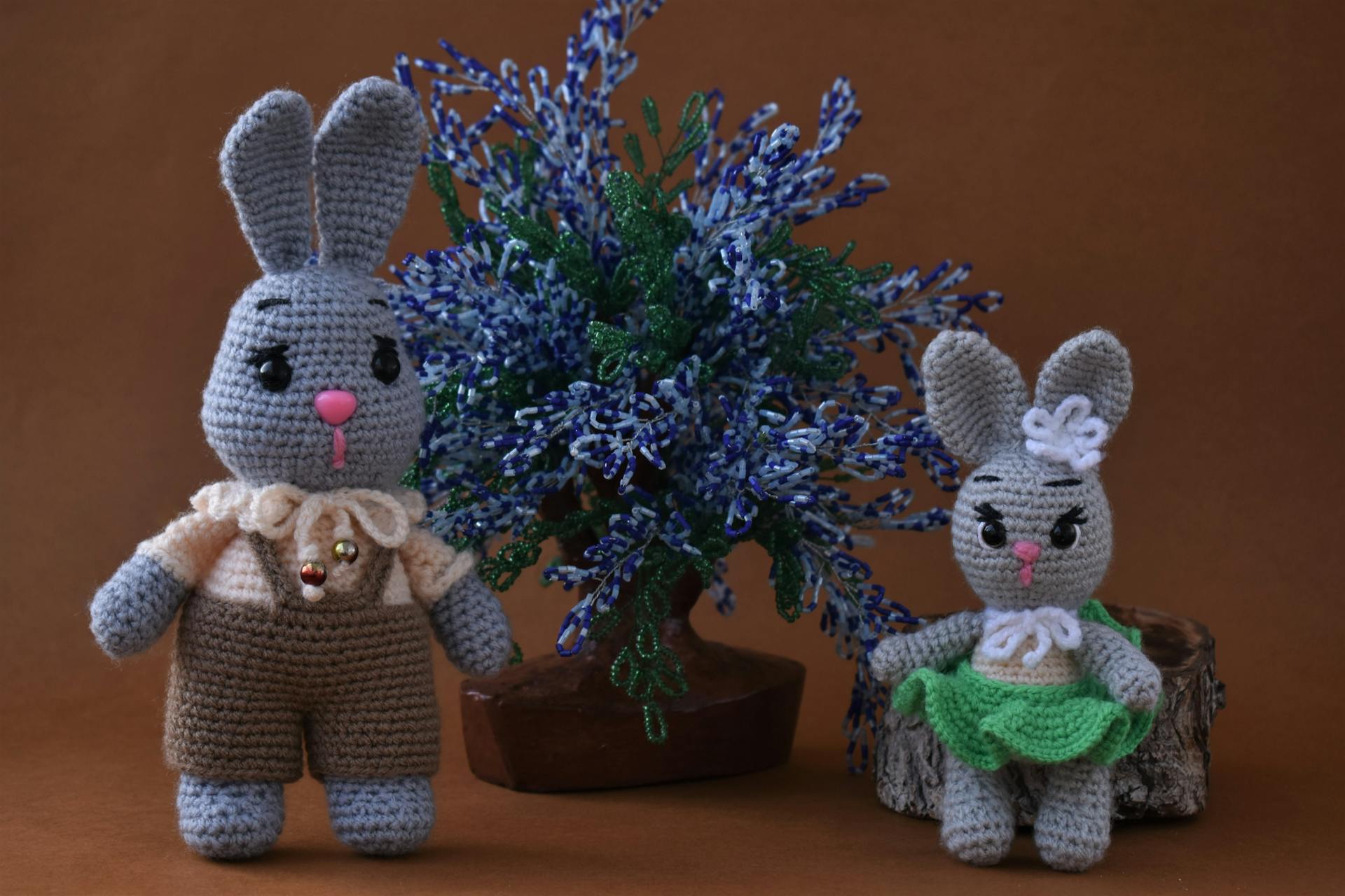 Two crochet bunnies next to a fake flower