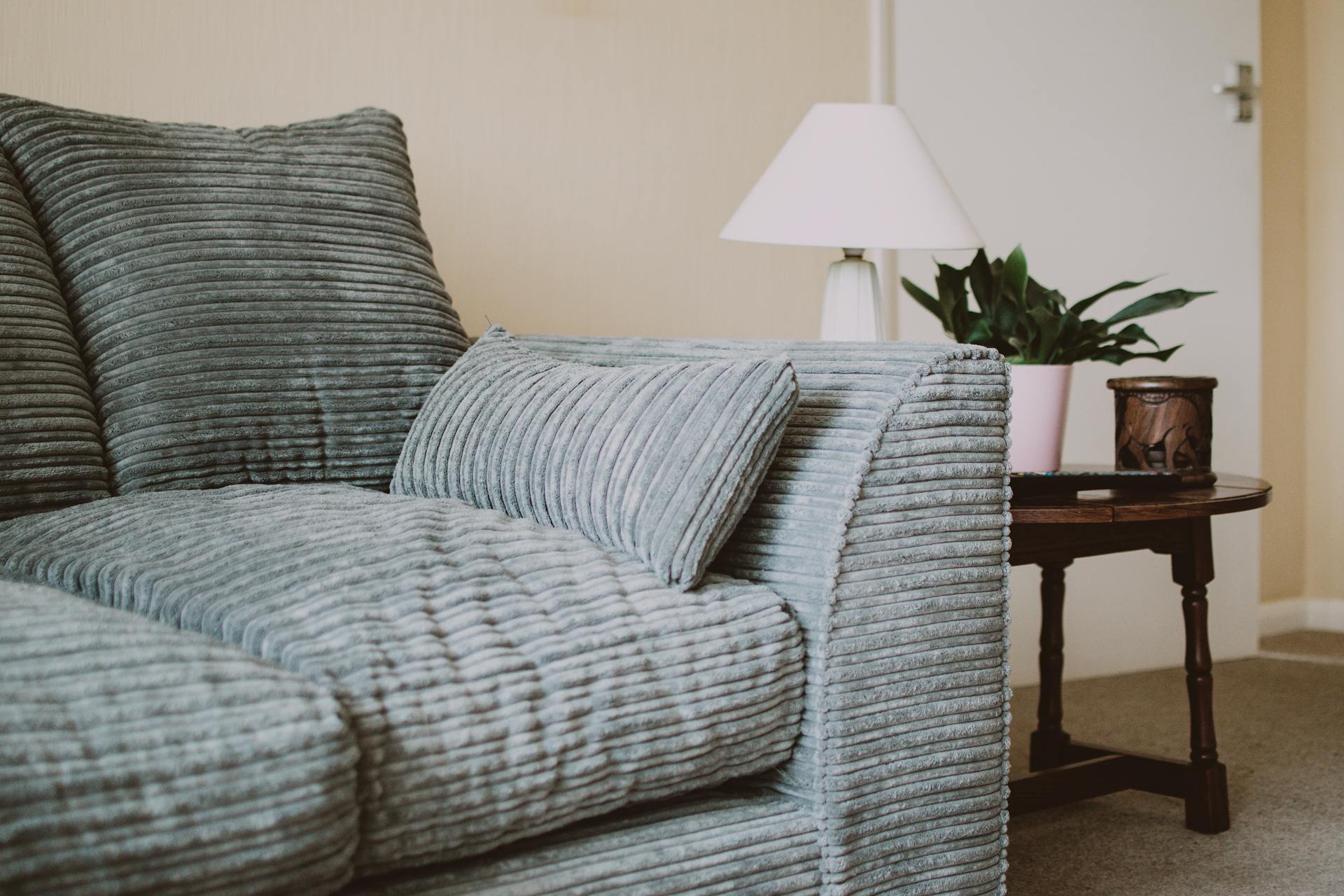 Gray couch seat with a nearby white lamp