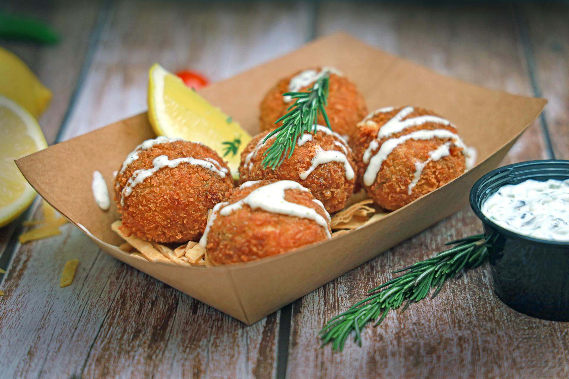 Crab cakes in a brown container with lemon slices