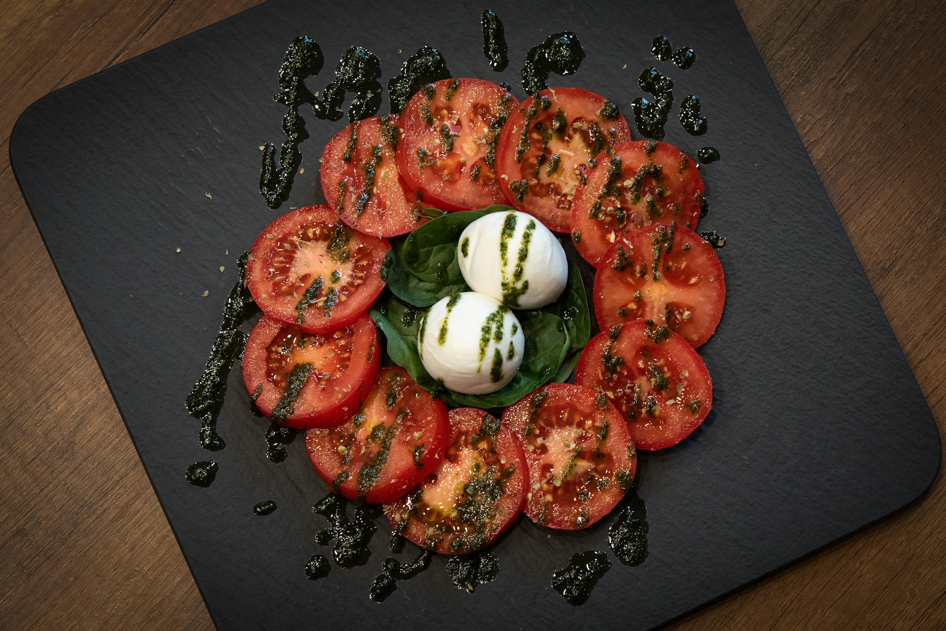 Caprese salad spread with tomatoes on a black background