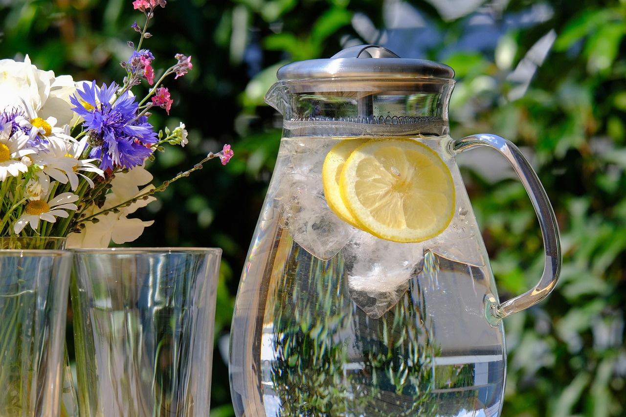 Pitcher of water with lemon slices and two cups nearby